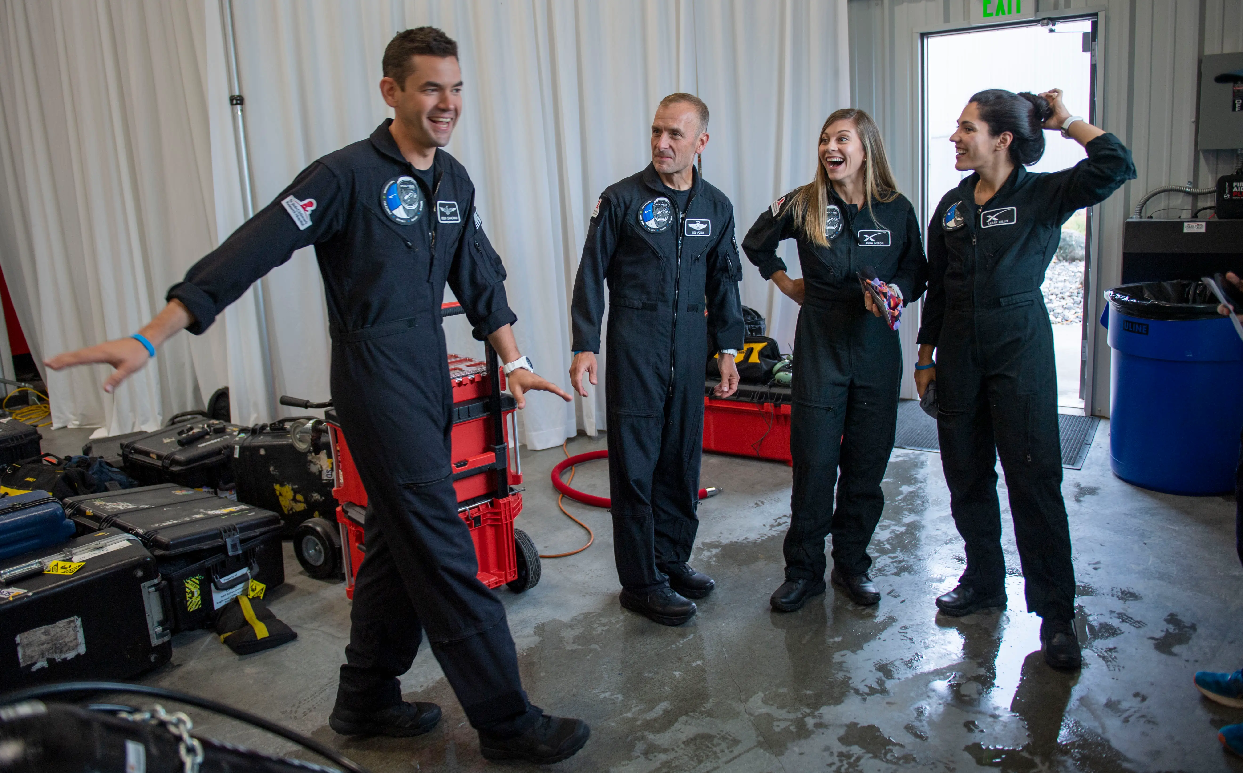 Jared Isaacman in space suit smiling with three people standing next to him