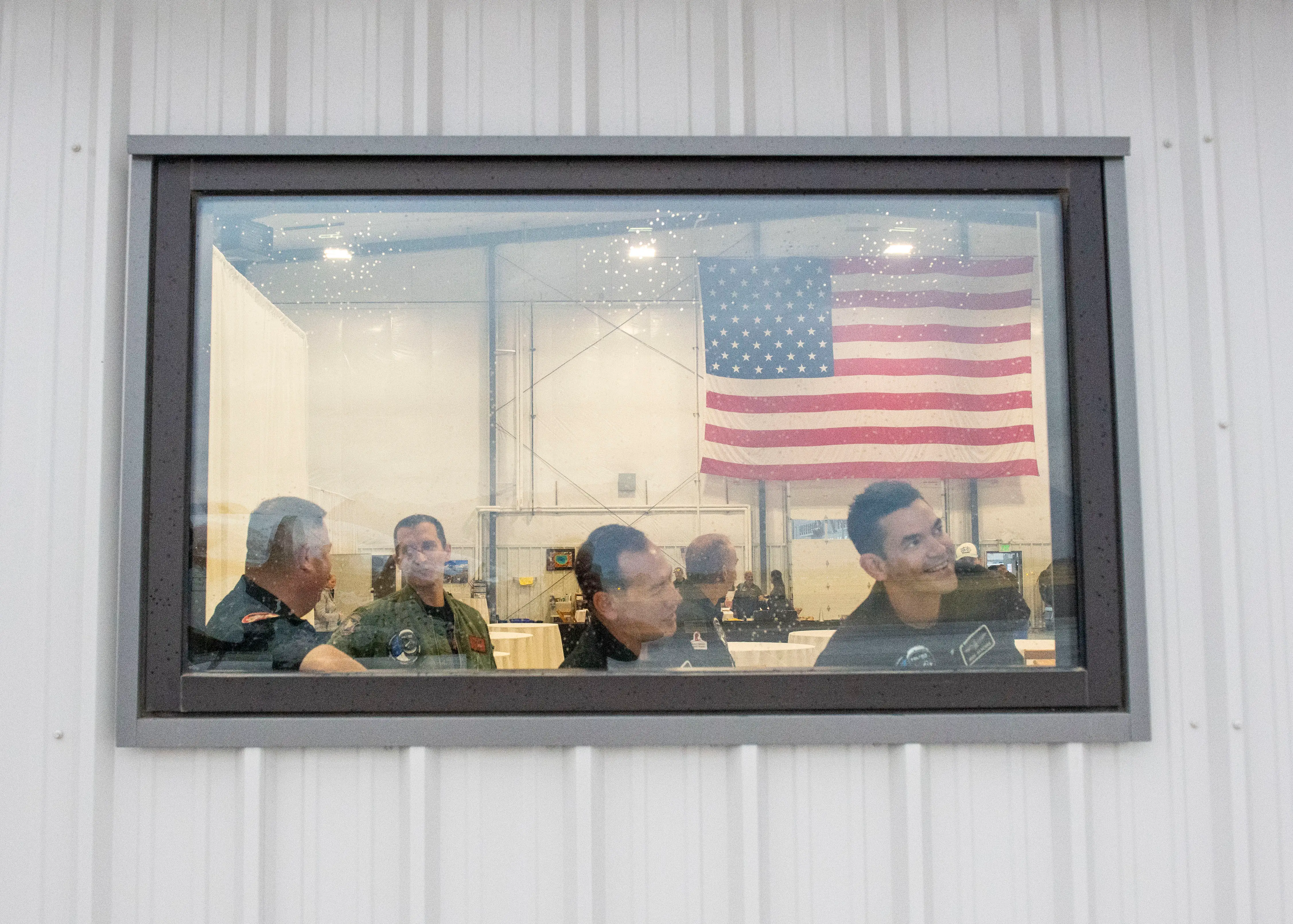Jared Isaacman smiling through window with American flag behind him