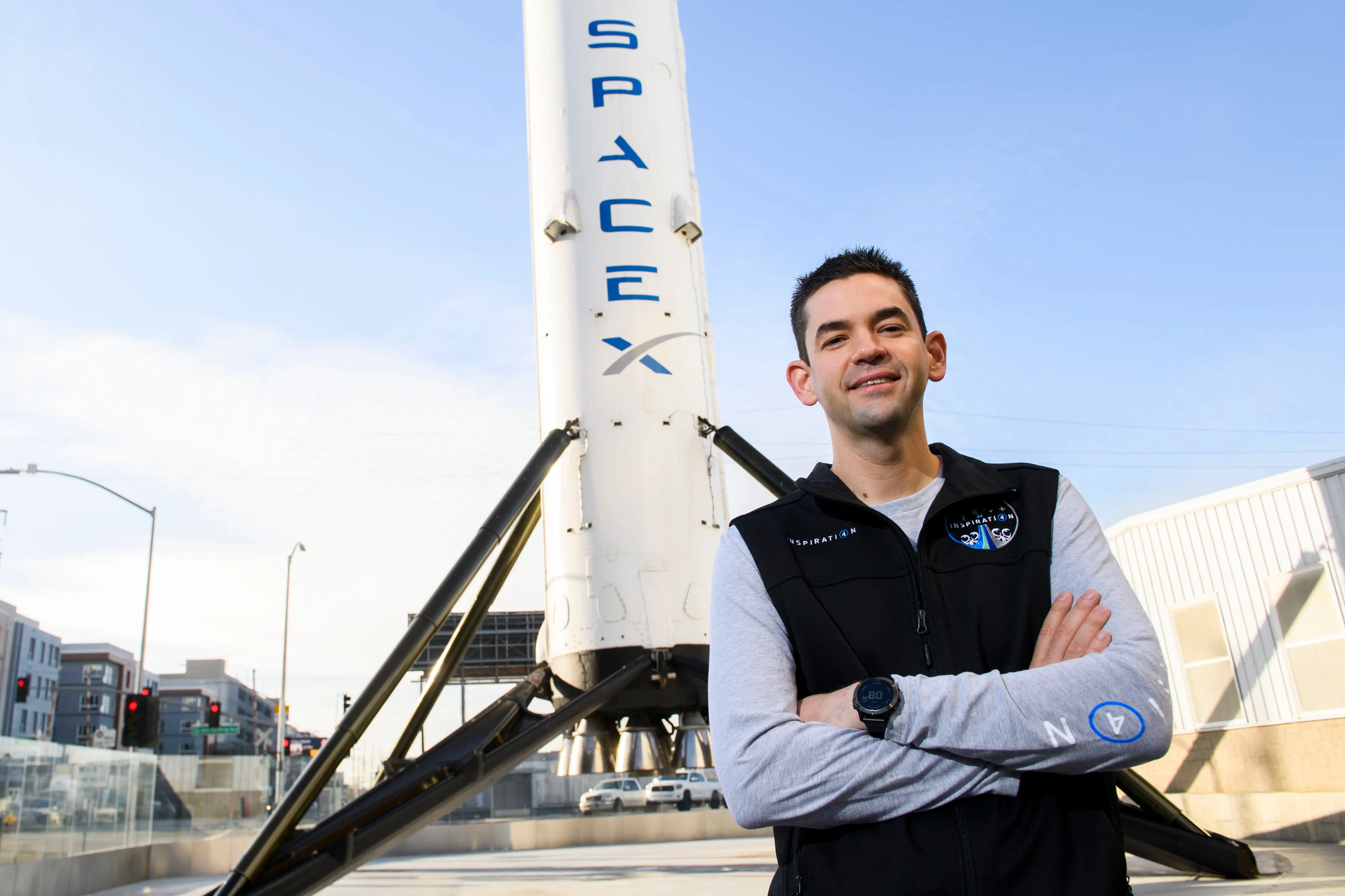 Jared Isaacman smiling with SpaceX rocket behind him.
