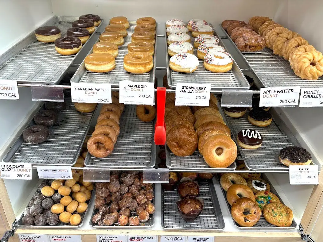 Three rows of doughnuts, croissants, bagels, doughnut holes, muffins, and cookies on display at Tim Hortons.