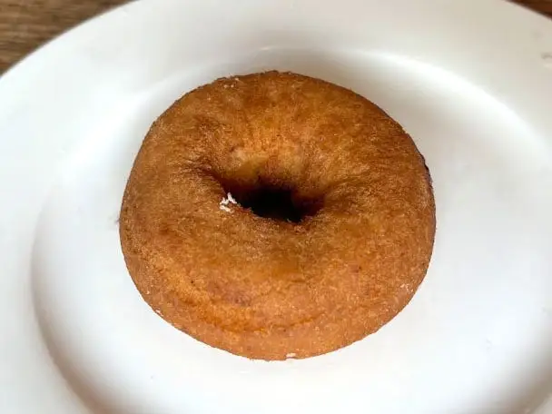 A plain cake doughnut on a white plate.