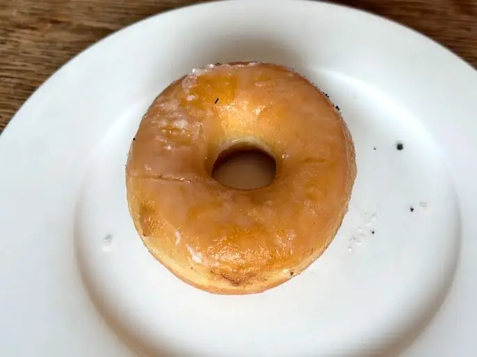 A doughnut topped with a glaze on a white plate.