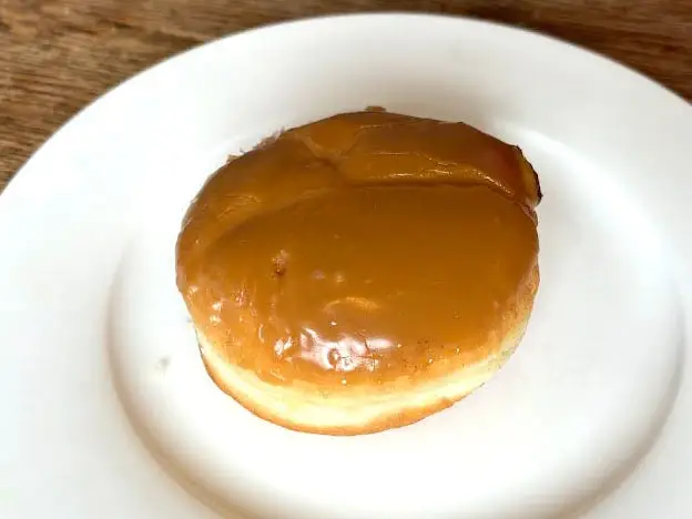 A doughnut with no hole on a white plate.