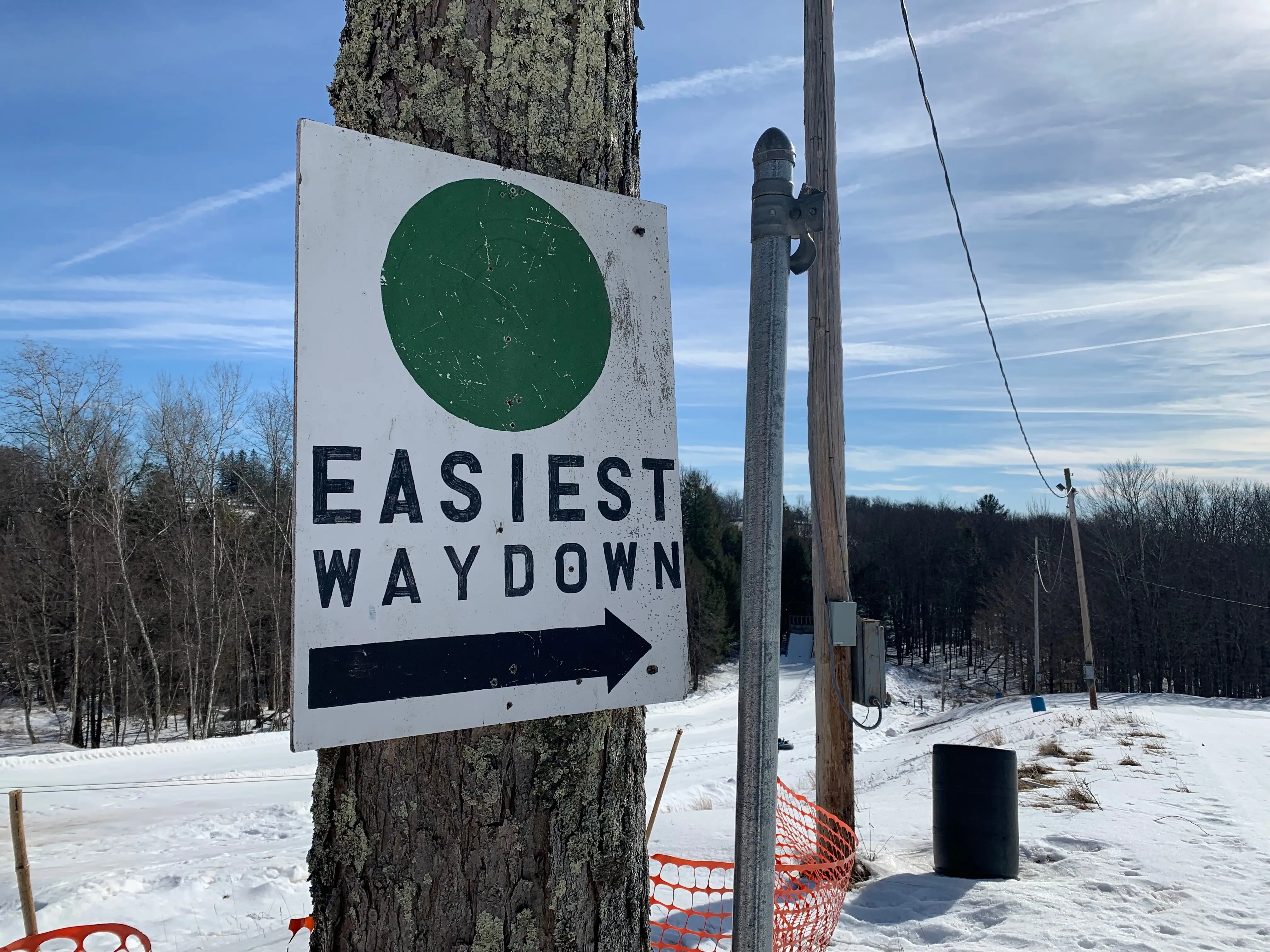 sign on a tree that says easier way down at a ski resort