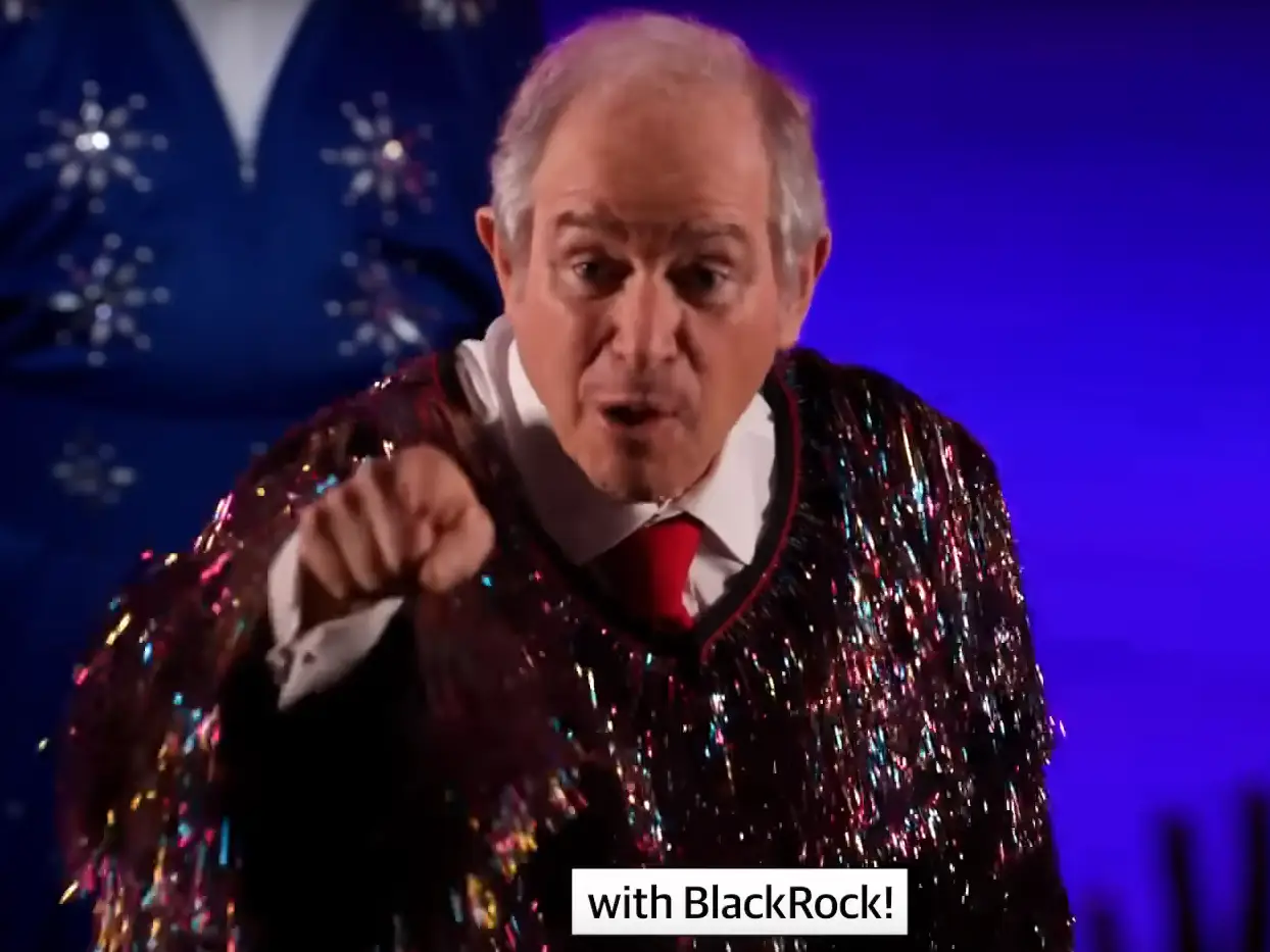 Steve Schwarzman dressed in a glittery shirt while pointing at the screen.