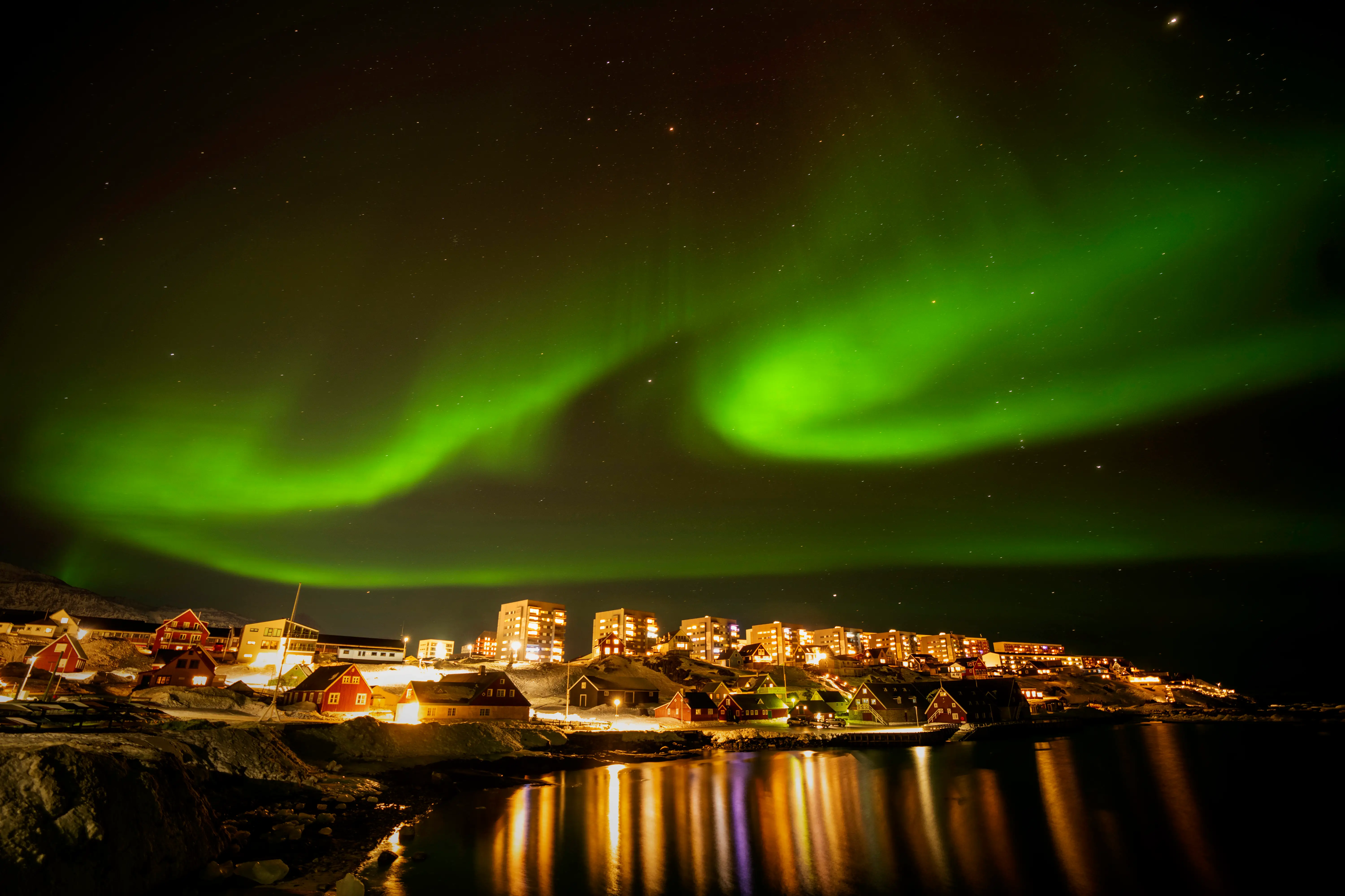The northern lights appearing as a greenish blur over Nuuk, Greenland