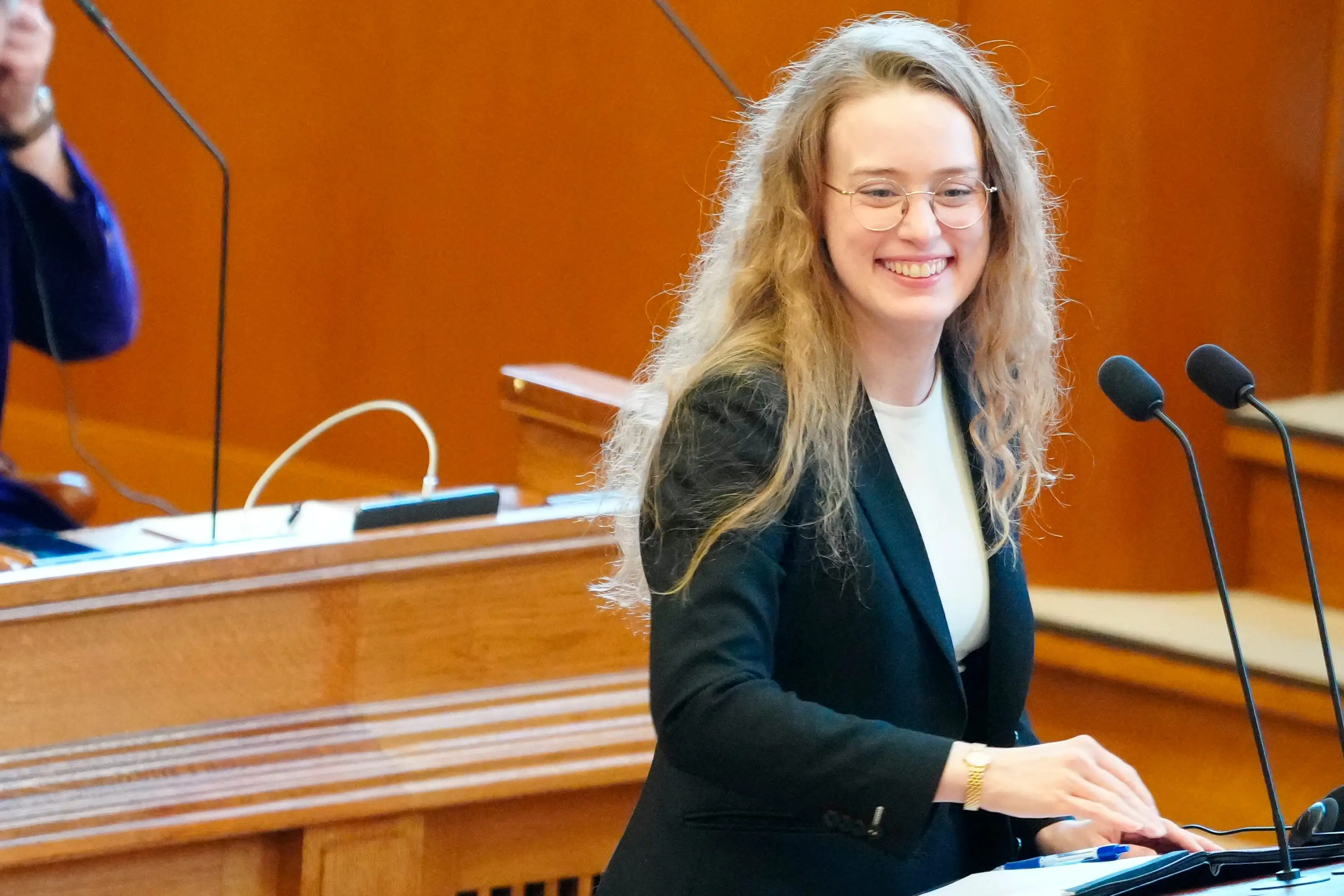 Greenlandic politician Aki-Matilda Hoeegh-Dam stands at a podium smiling