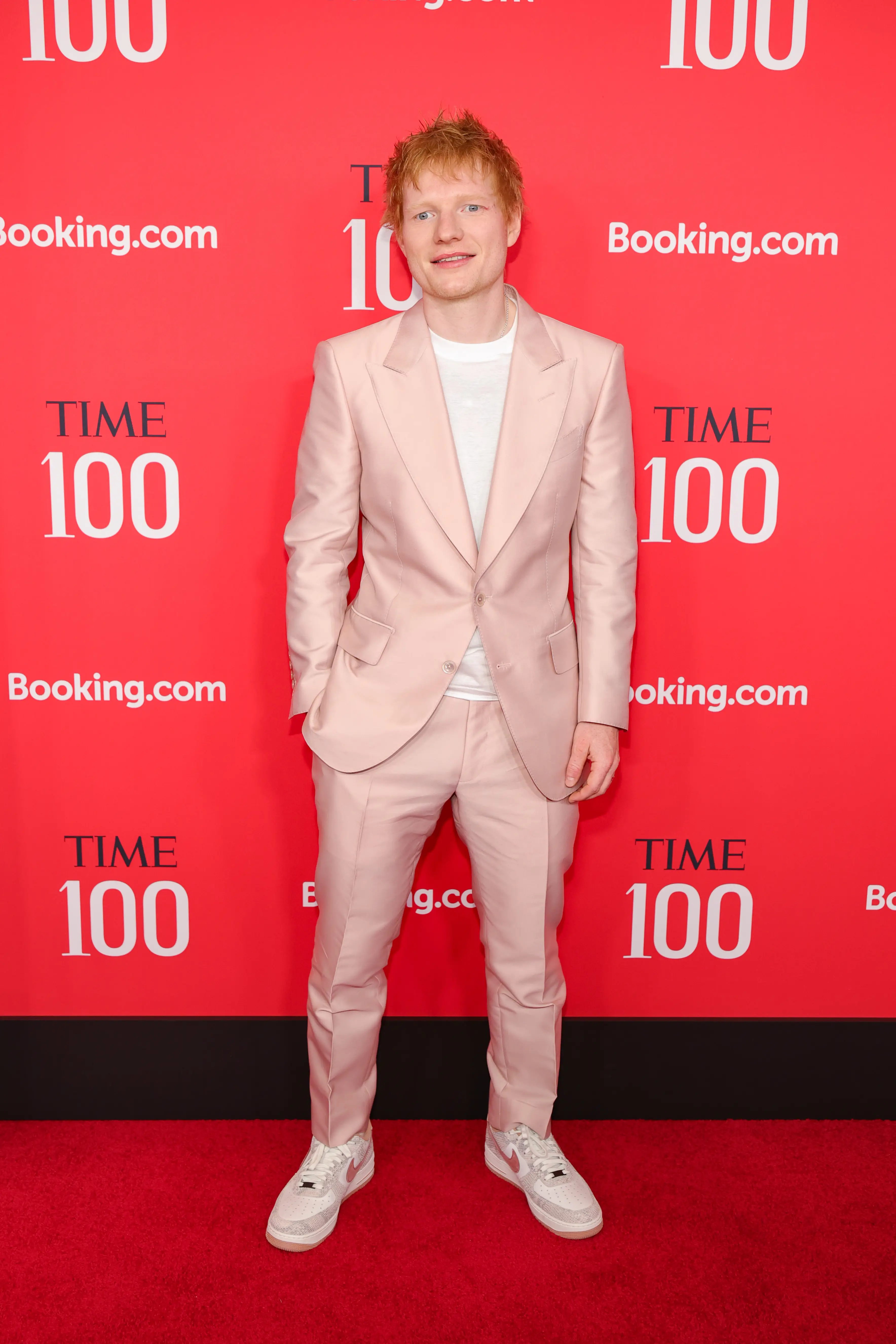 Ed Sheeran wearing a light-pink suit, white T-shirt, and white sneakers on the Time100 Gala red carpet.