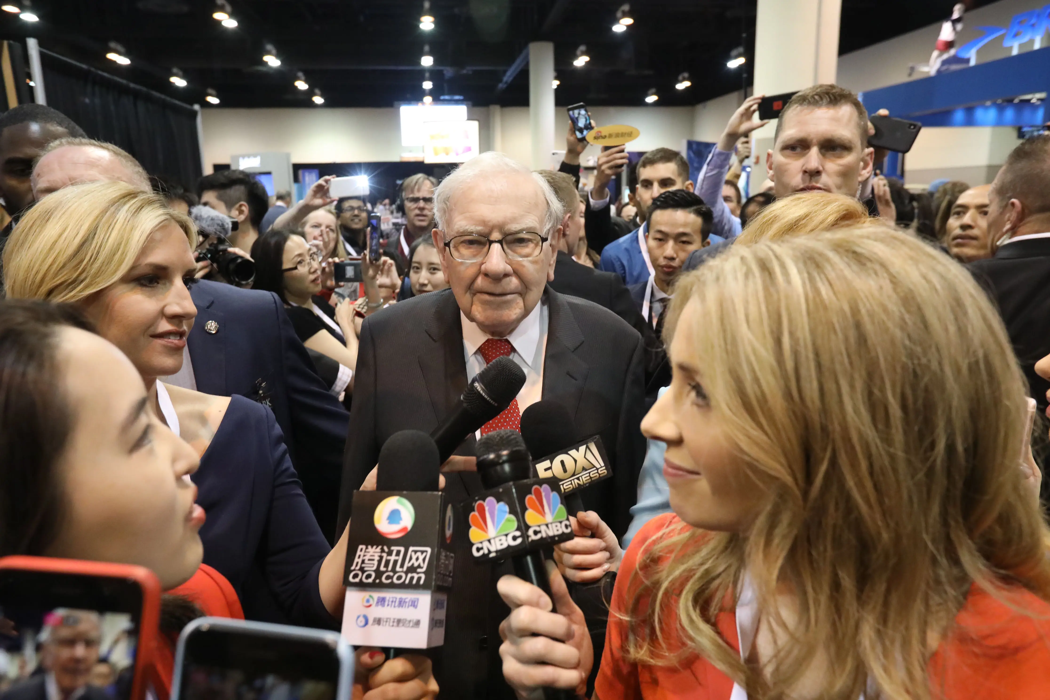 Warren Buffett, surrounded by journalists' microphones