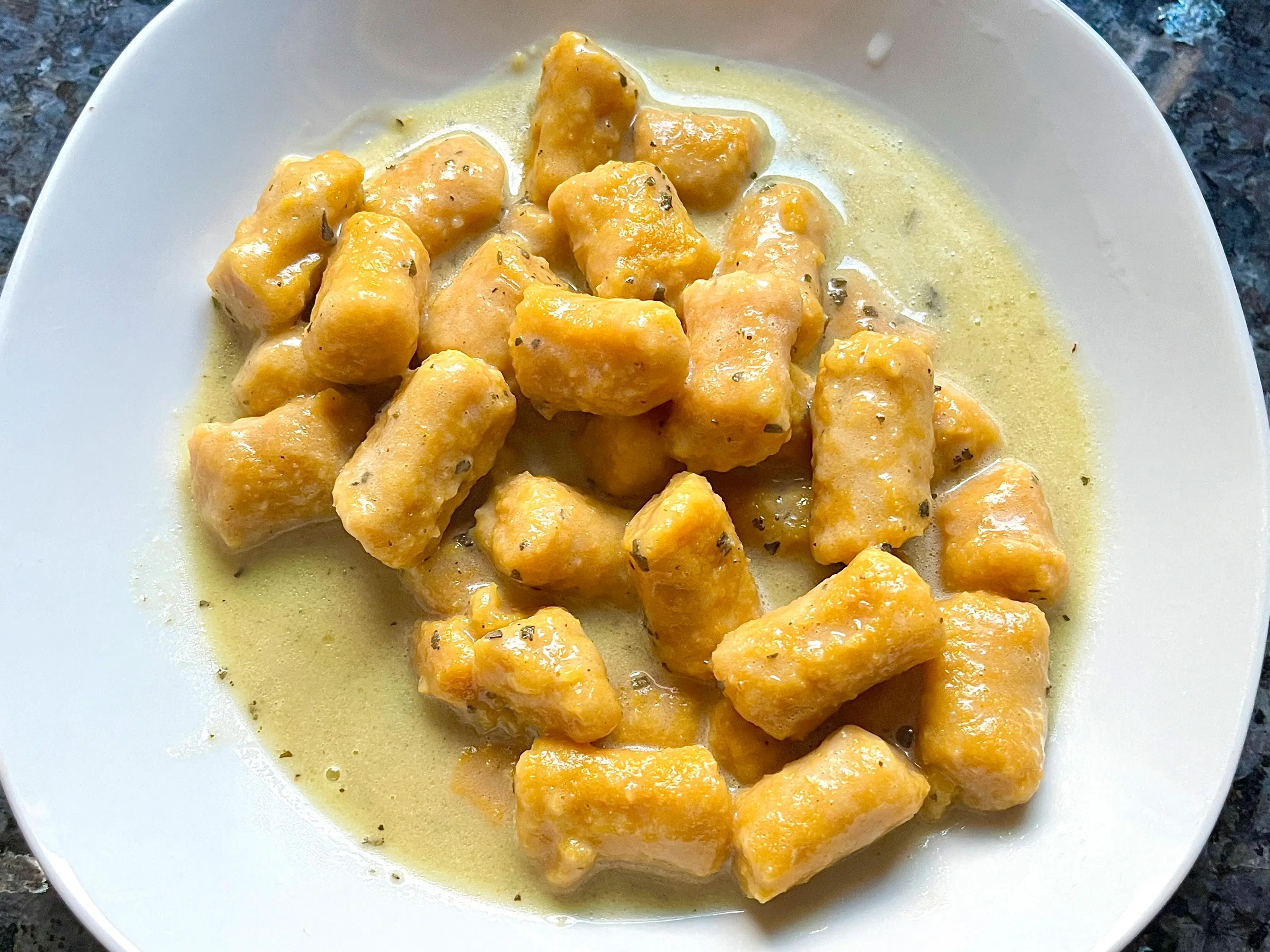 A plate of sweet potato gnocchi with butter and sage sauce.