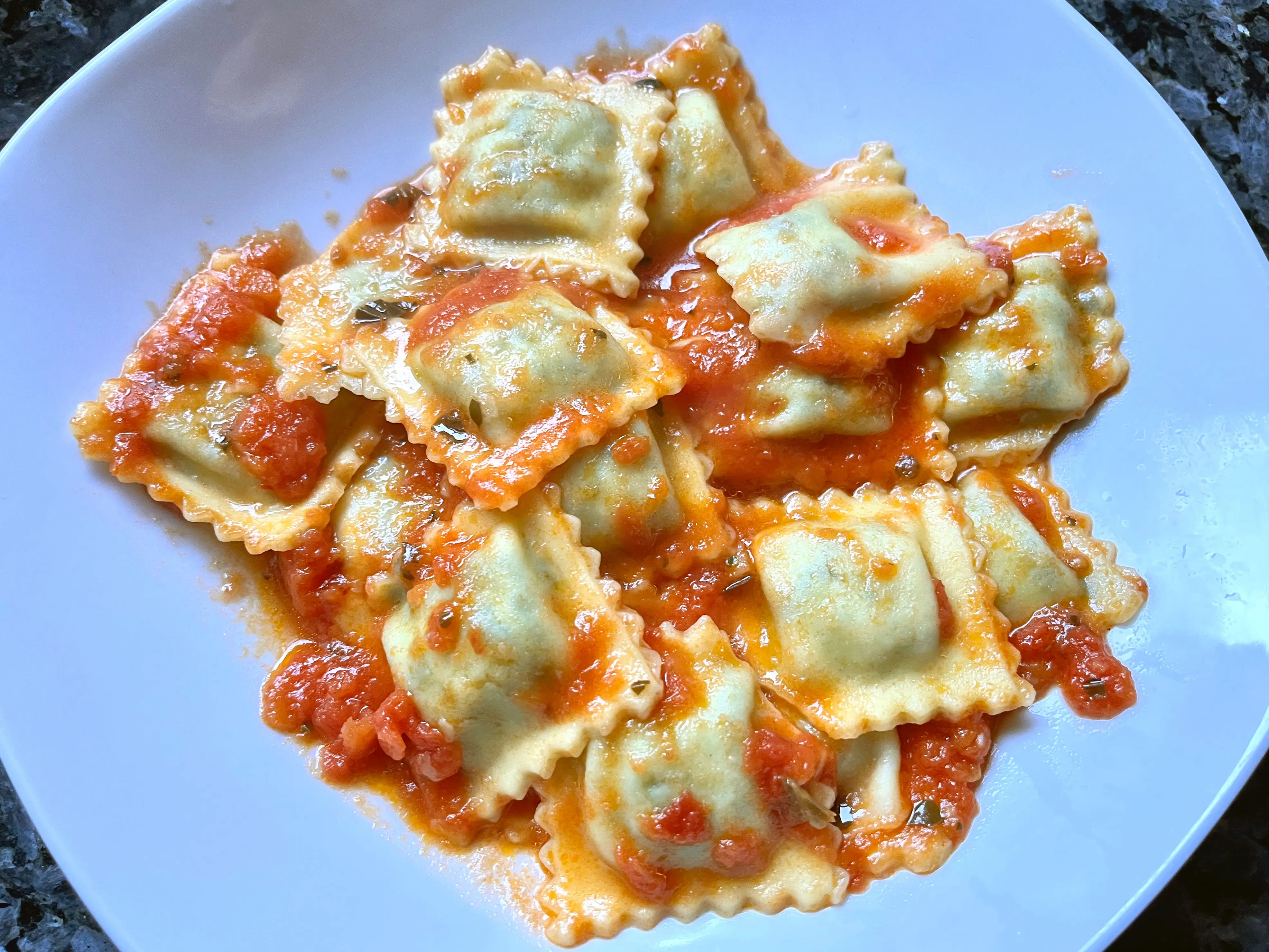 A plate of small ravioli in red sauce.