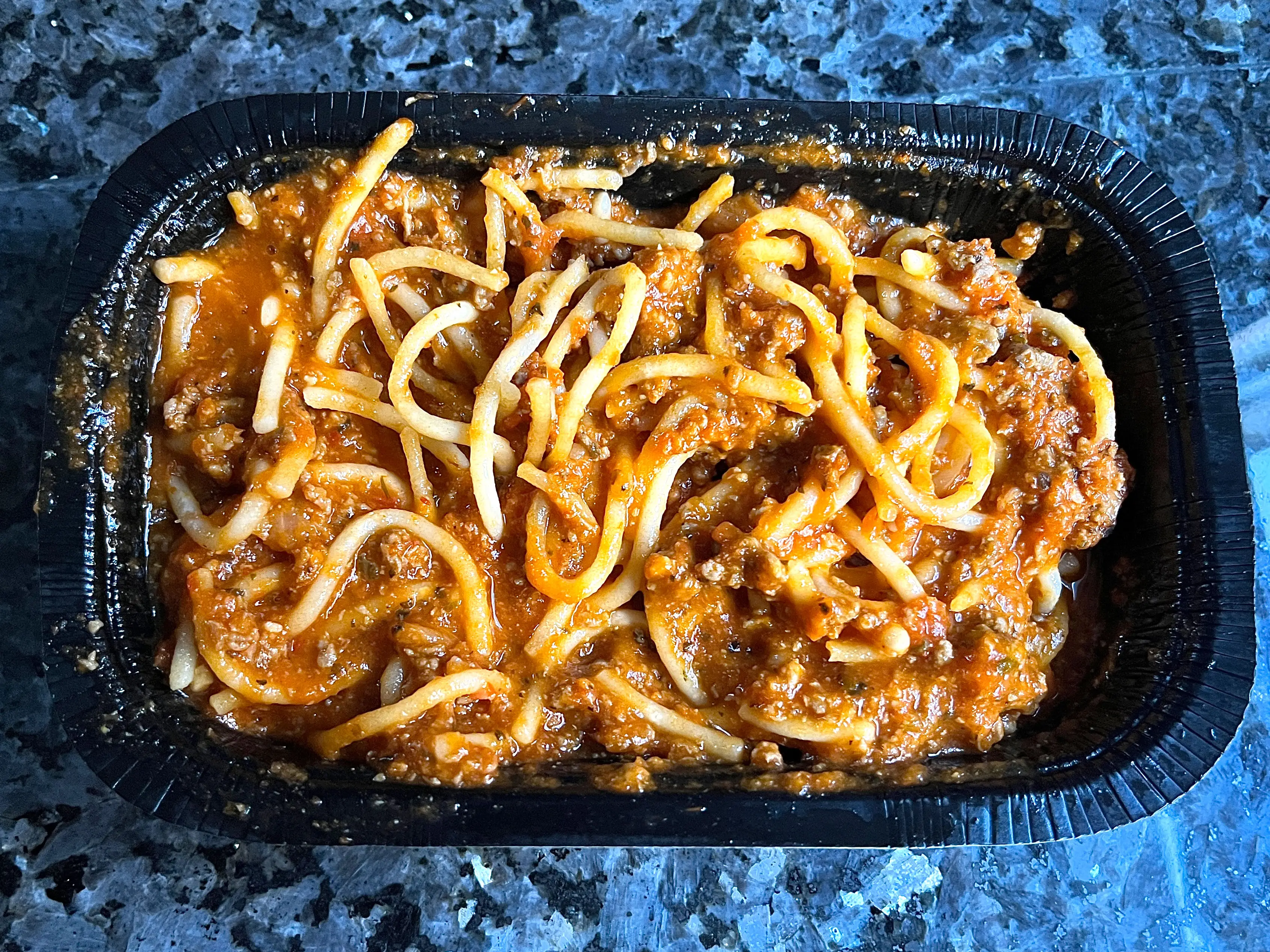 A container of spaghetti with meat sauce.