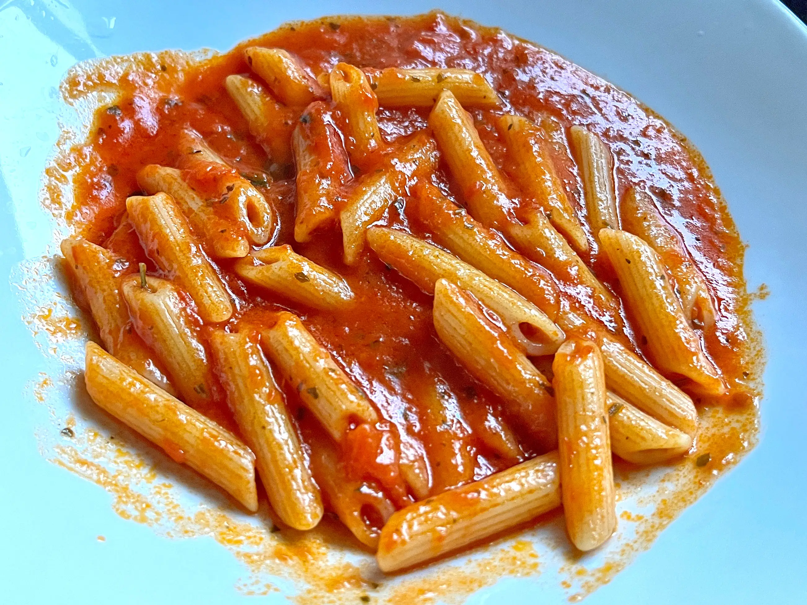 A plate of penne in a red sauce.