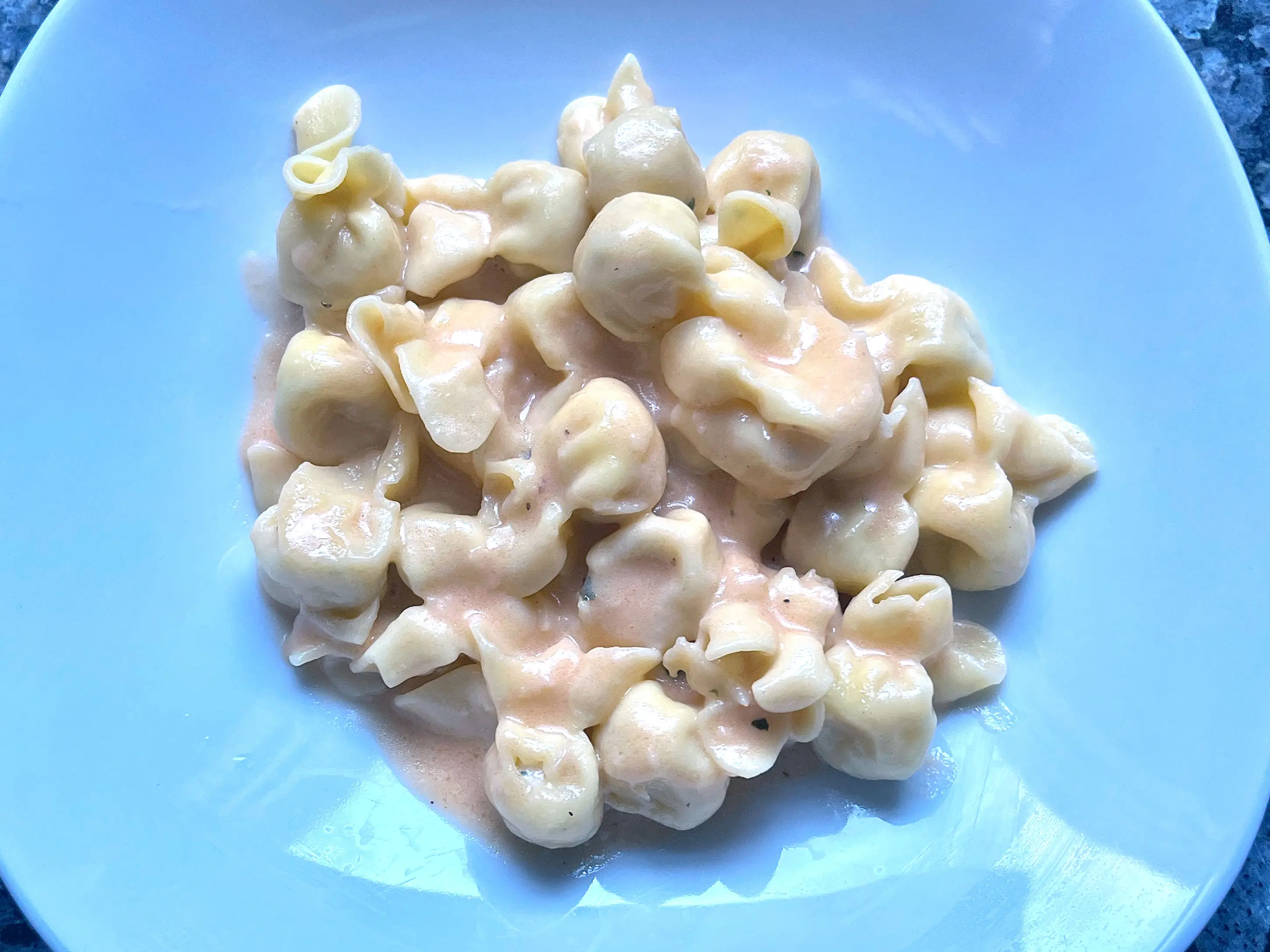 A plate of fiocchetti pasta with pink sauce.