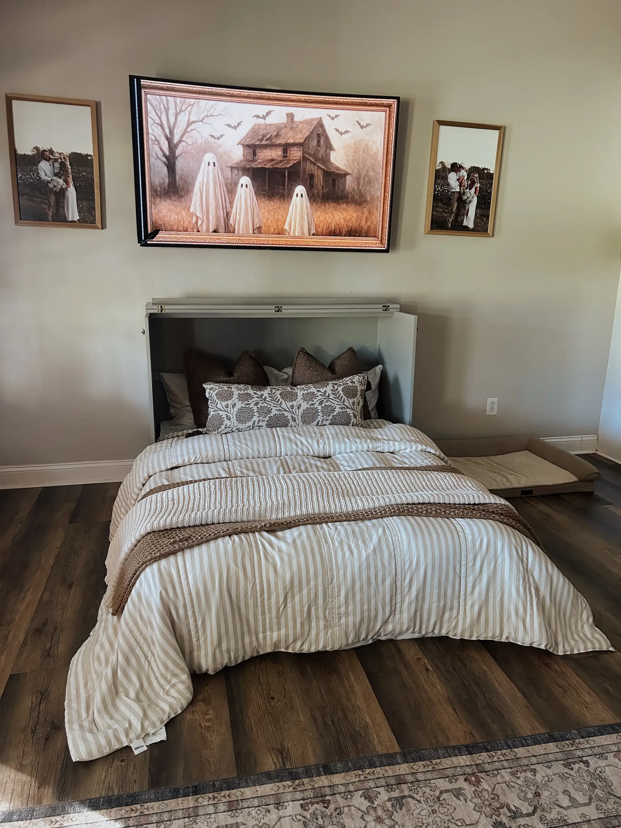 A Murphy bed built into a cabinet sits under a TV screen with a picture of ghosts on it.