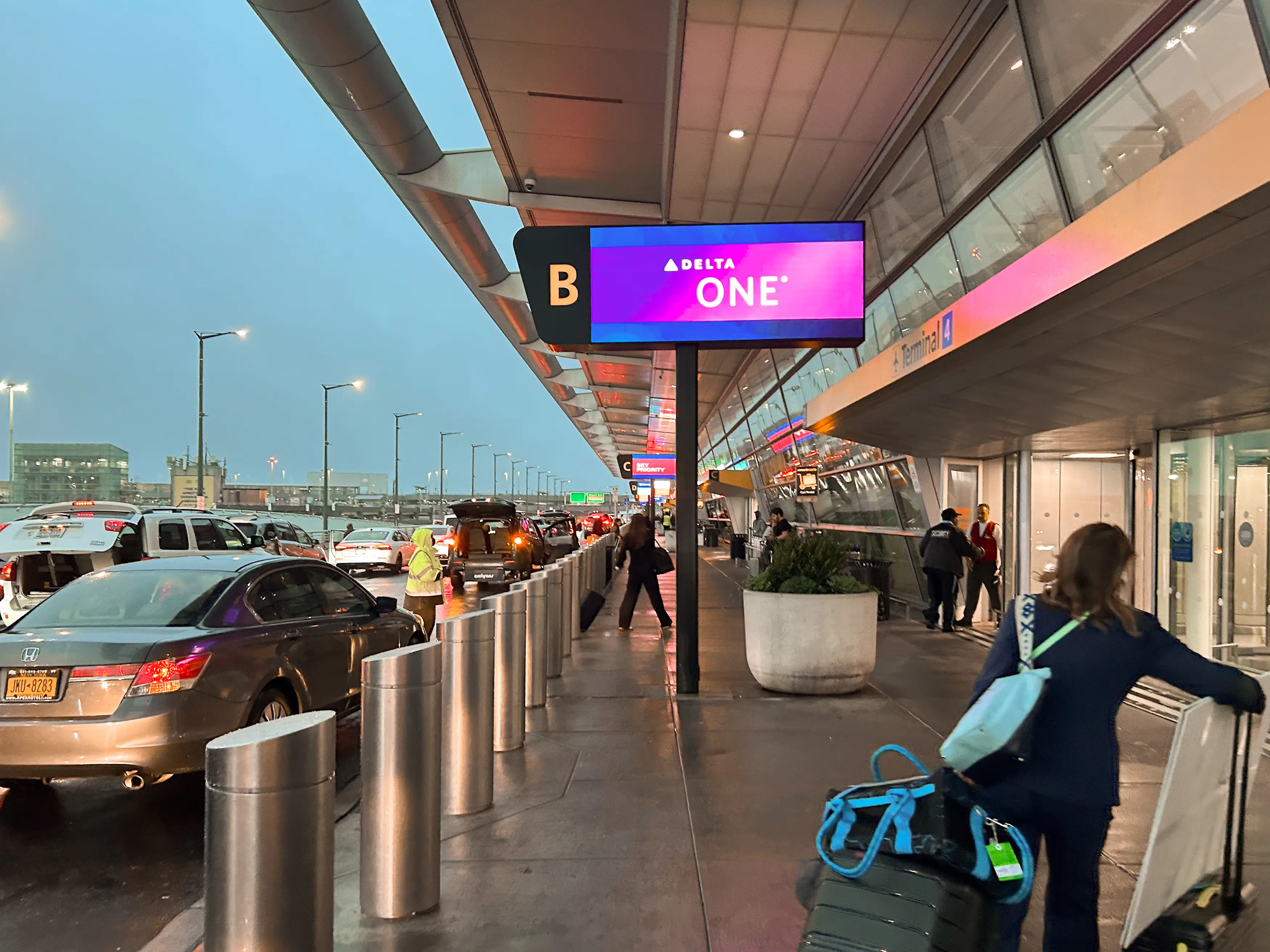 The entrance to an airport terminal with cars on the left, the terminal on the right, and Delta One signage in the middle