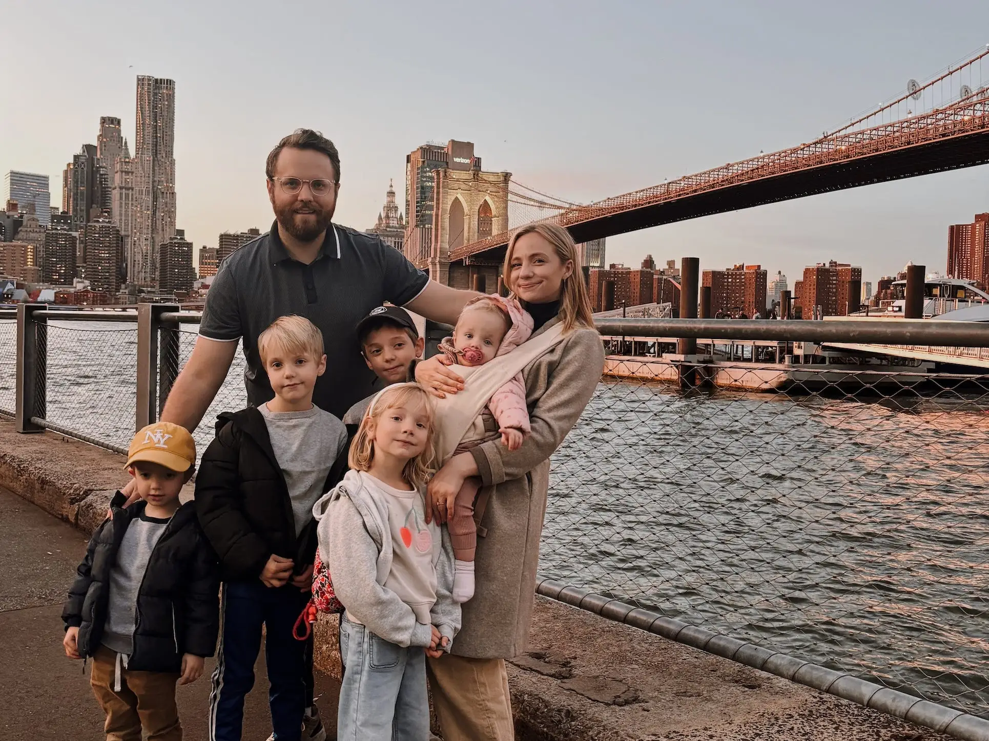 A couple with five children pose in front of the Brooklyn Bridge.