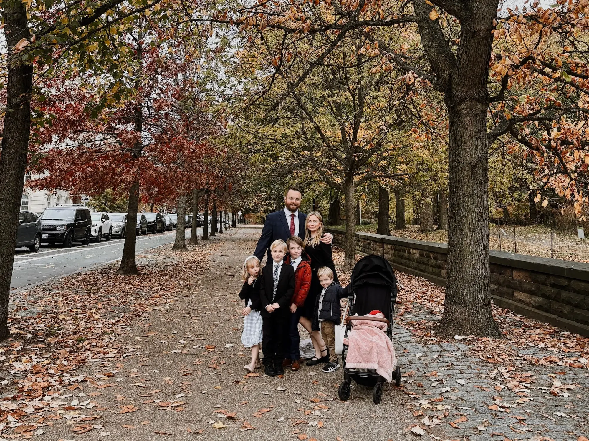A family of seven on a tree-lined street in New York City during autumn.