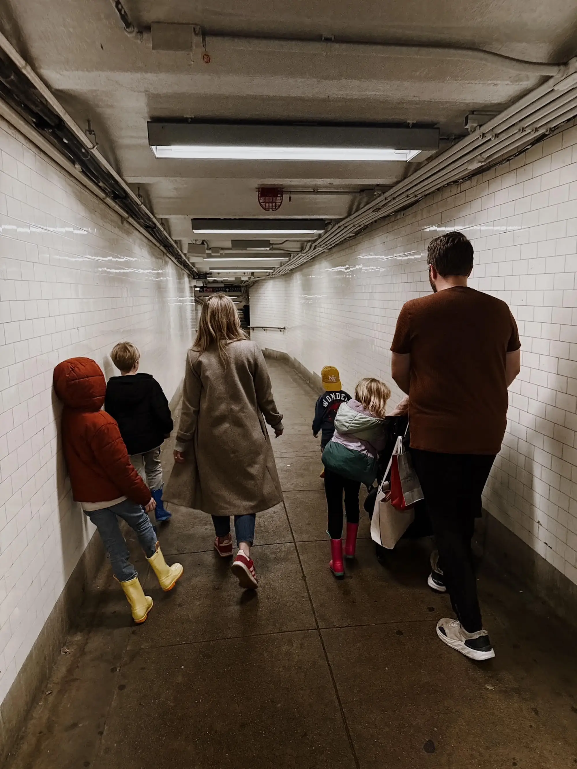 A family of seven walks through a tunnel of a subway station.