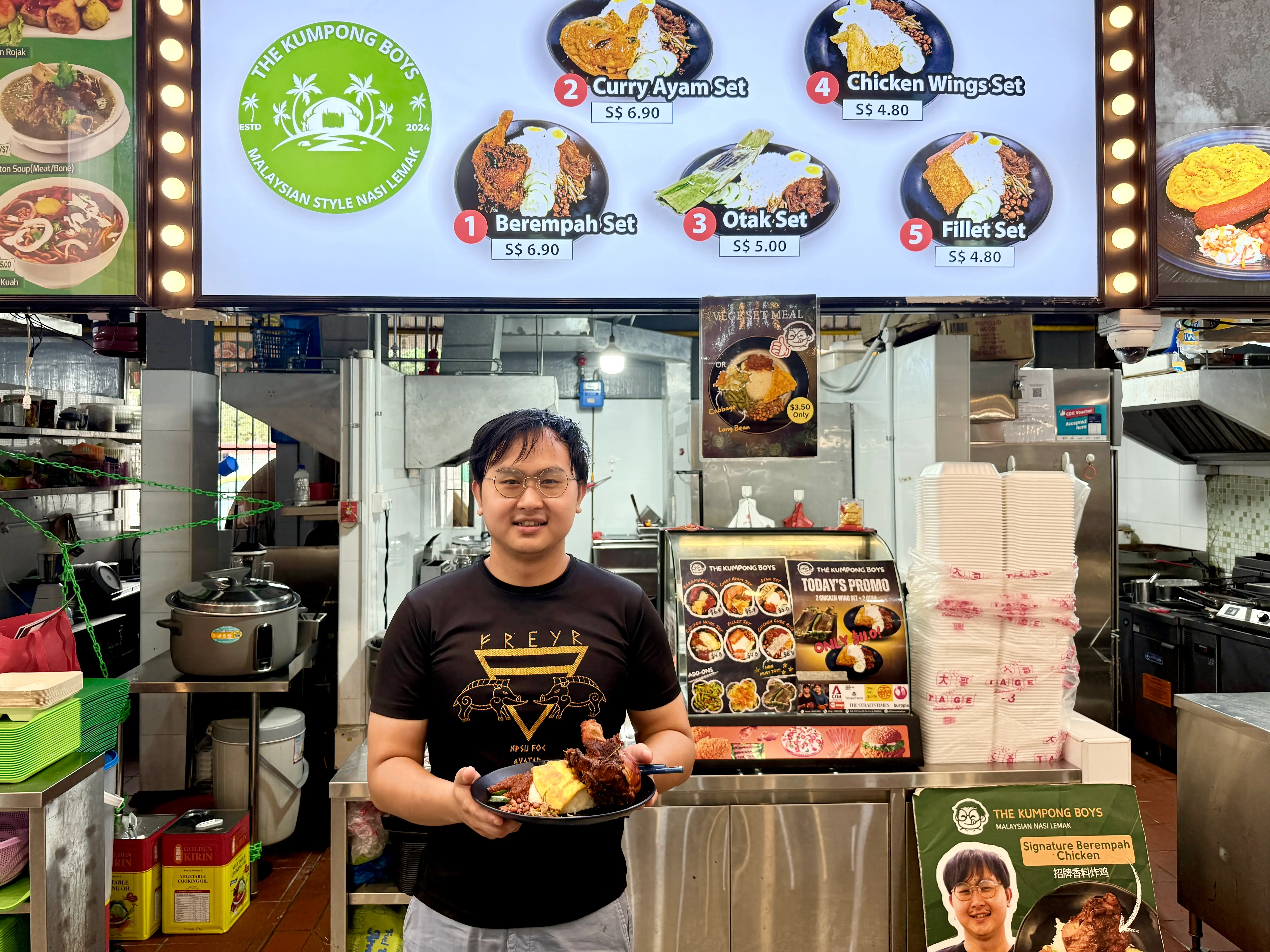 Jonas Koh holding a plate of nasi lemak in front of his stall, 