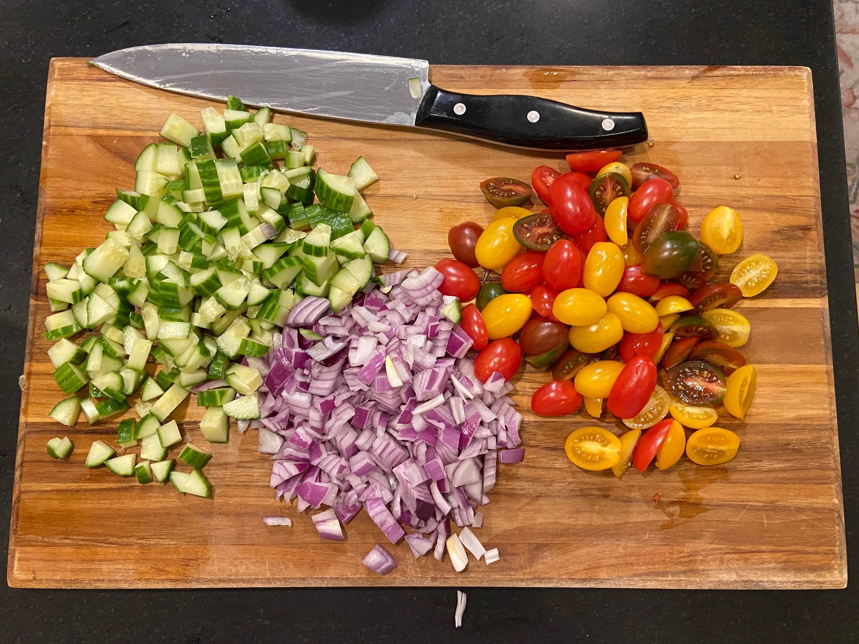 chopped cucumbers, onion, and tomatoes on cutting board