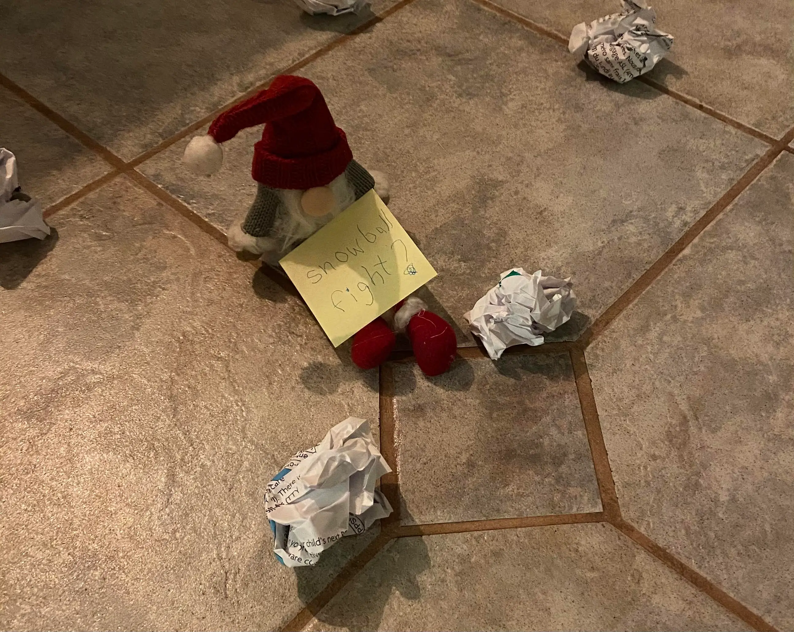 The Elf on the Shelf sitting in balled up paper with a post-it note that says 
