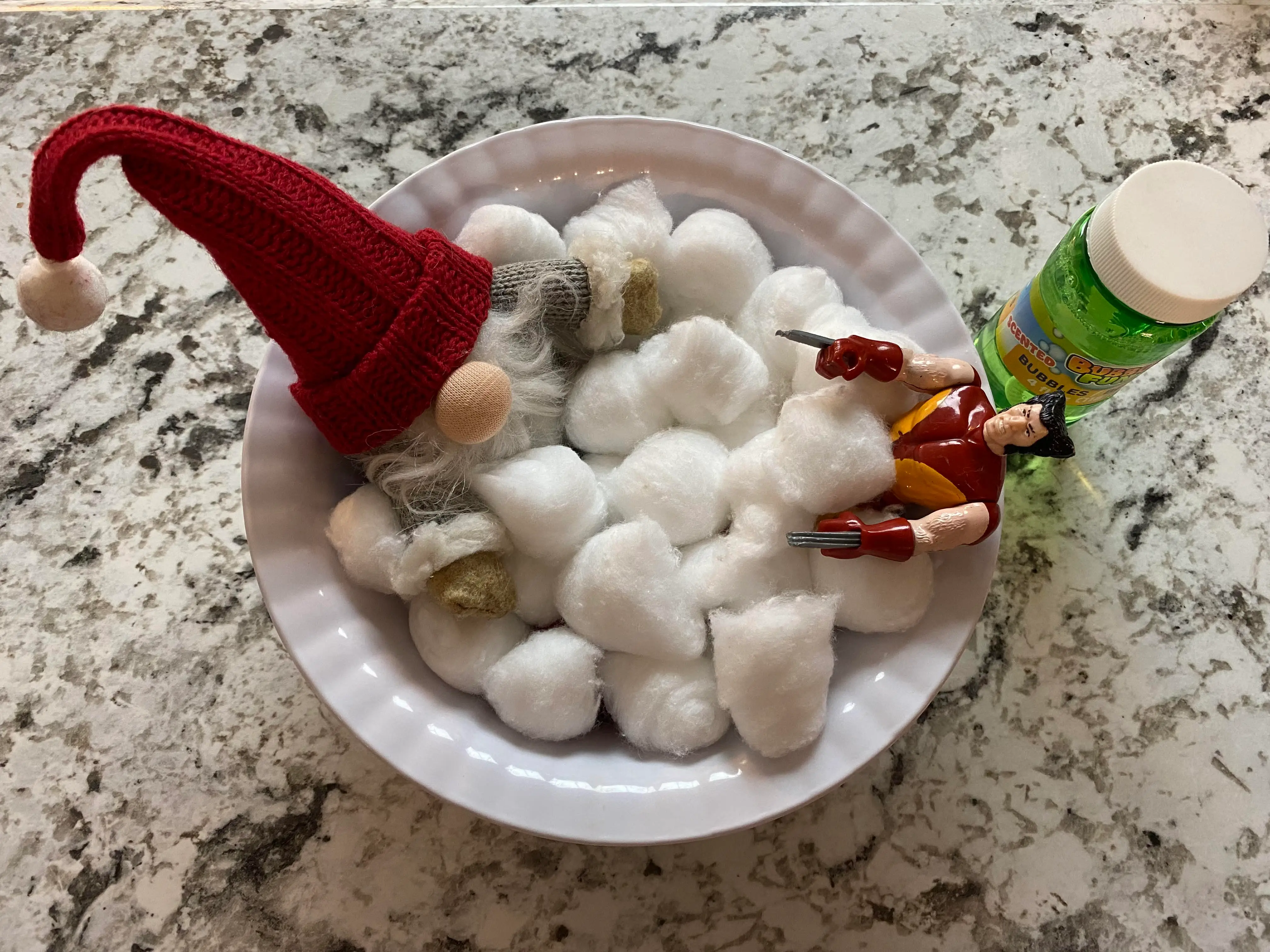 The Elf sitting in a bowl of cotton balls with an action figure