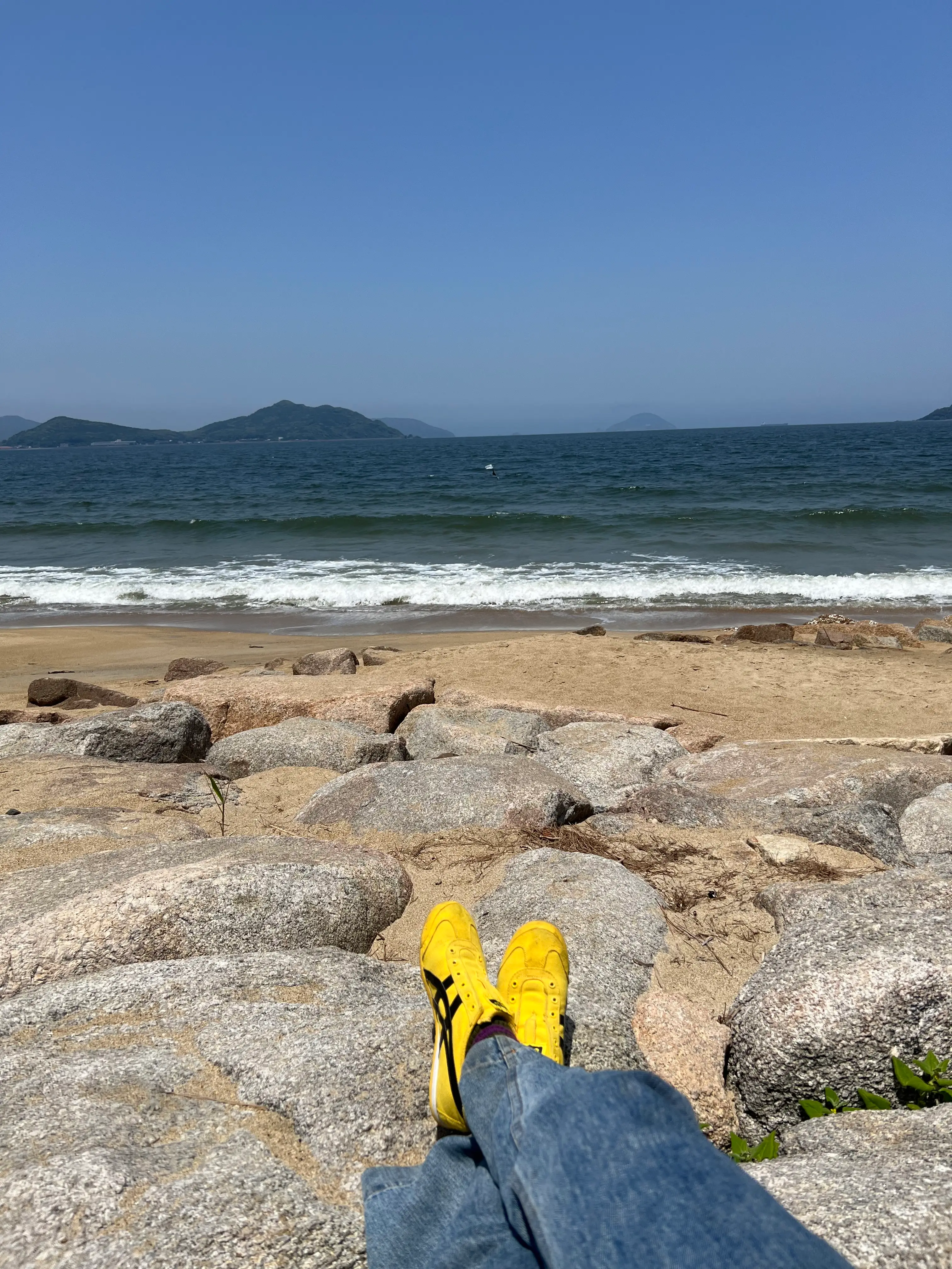 Yellow sneakers on a rock near the sea in Japan.