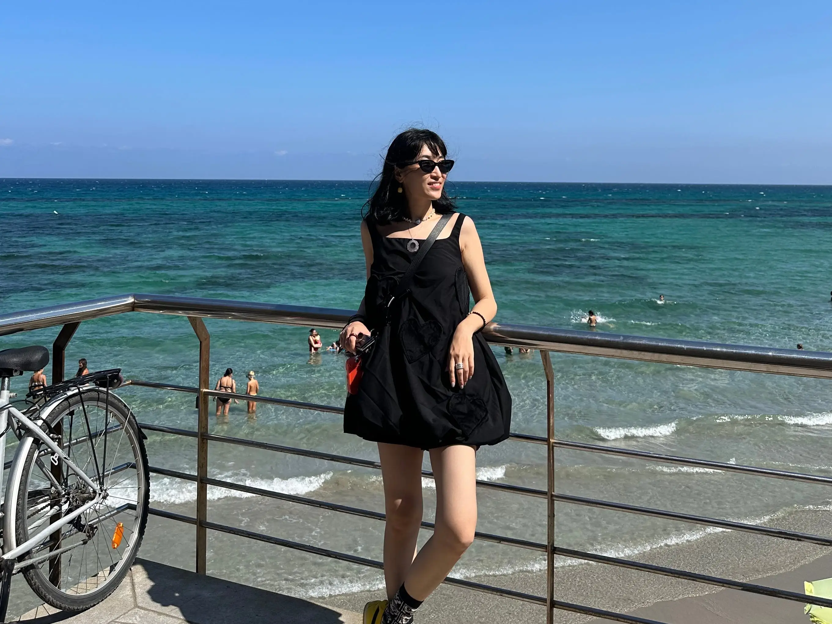 Woman in black dress posing near the sea in Italy.