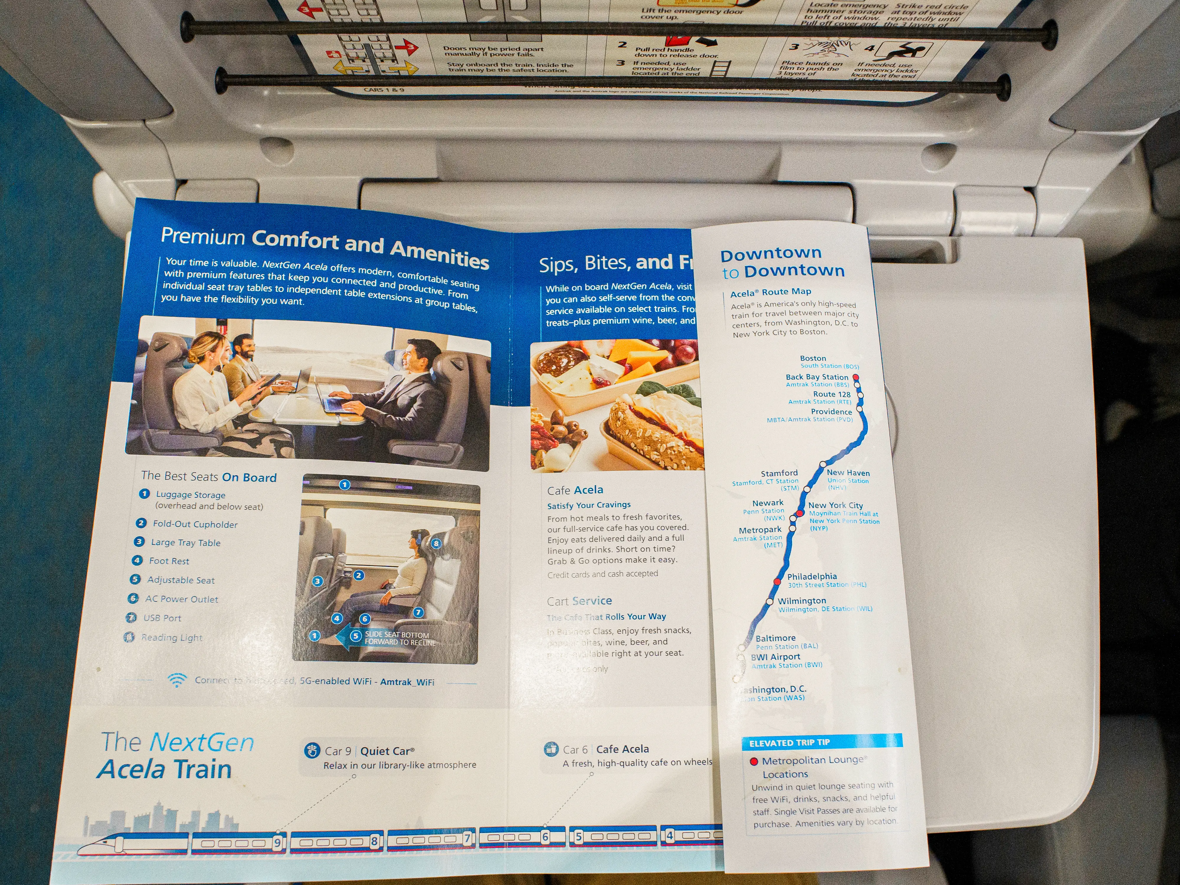 An aerial view of an Amtrak NextGen Acela pamphlet opened on a tray table
