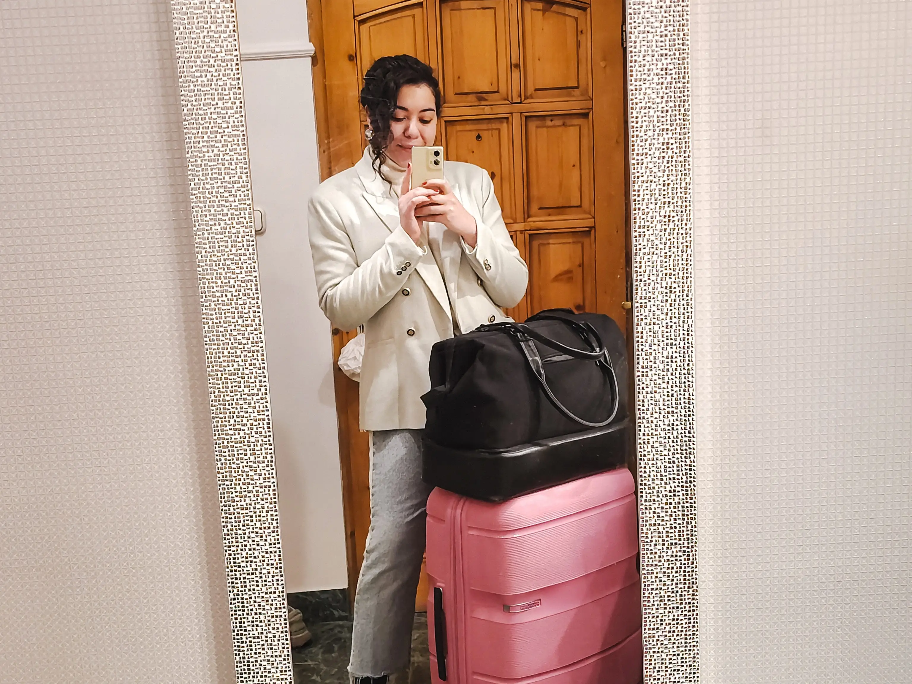 The author taking a mirror selfie with her suitcases in Budapest.