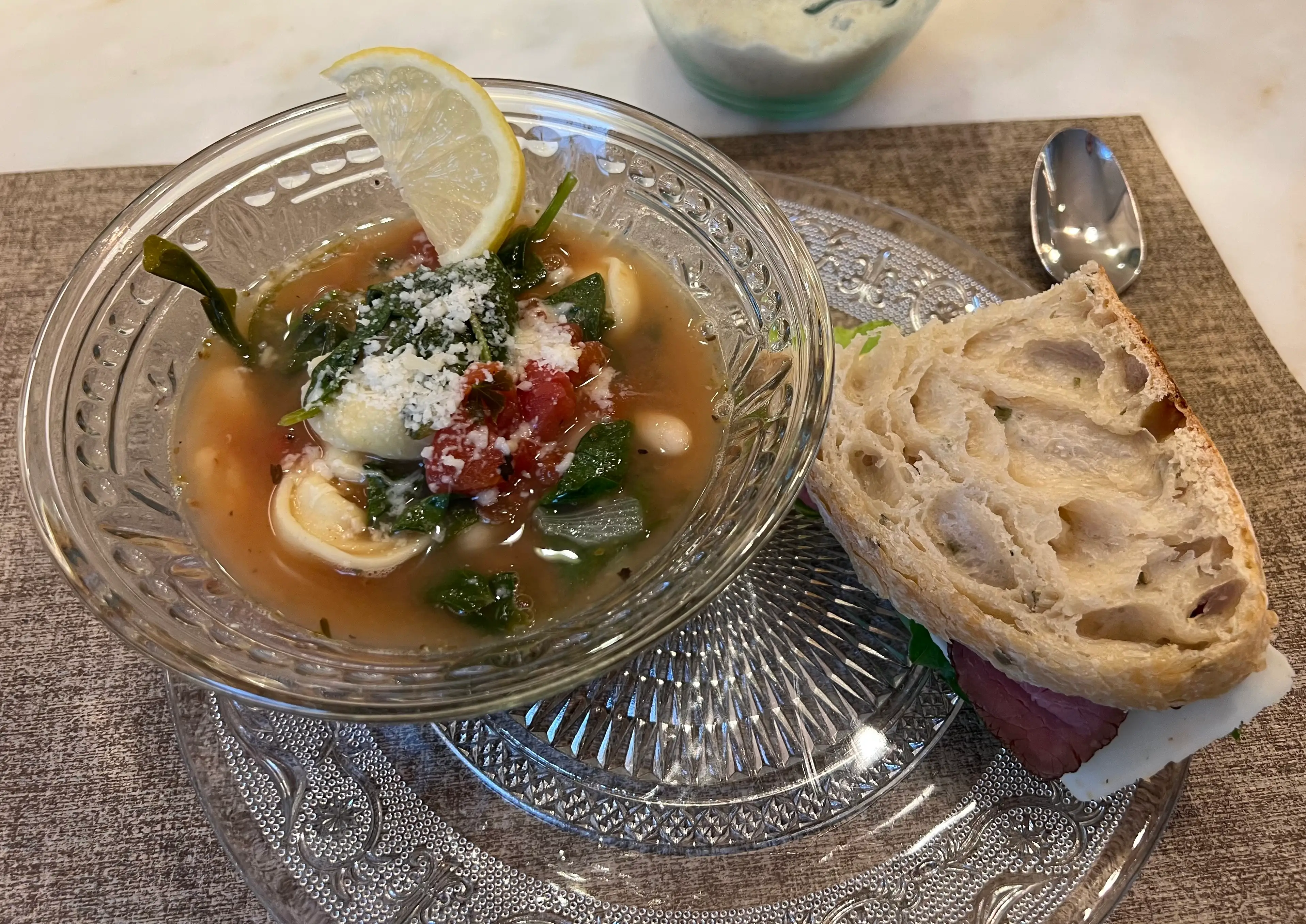 A bowl of soup with a piece of French bread next to it.