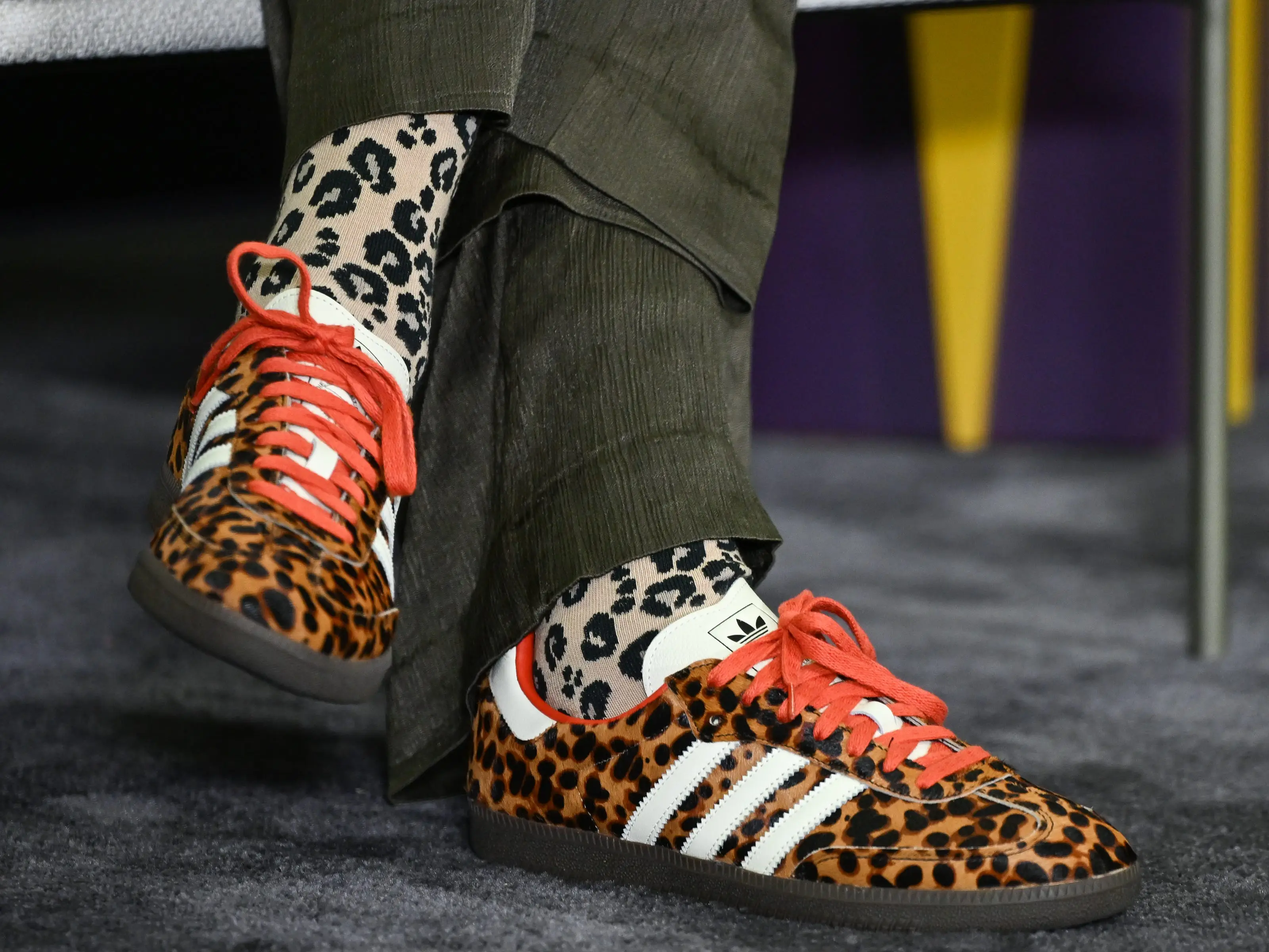 A close-up of someone wearing leopard print Adidas Sambas.
