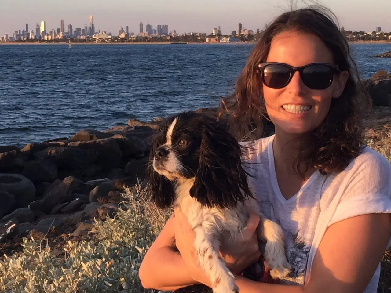 Woman smiling with dog near water in Australia