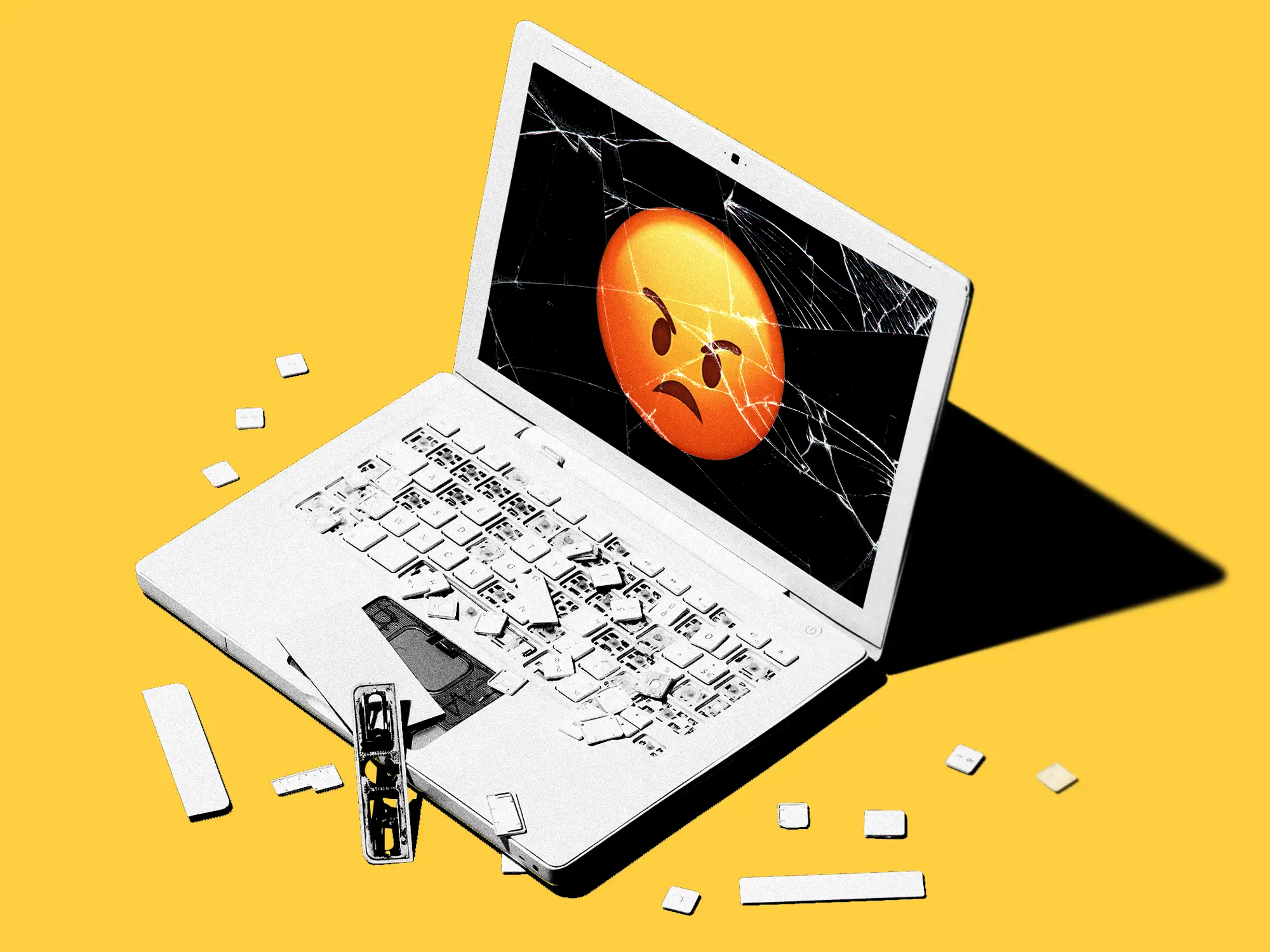 A shattered laptop displaying an angry emoji