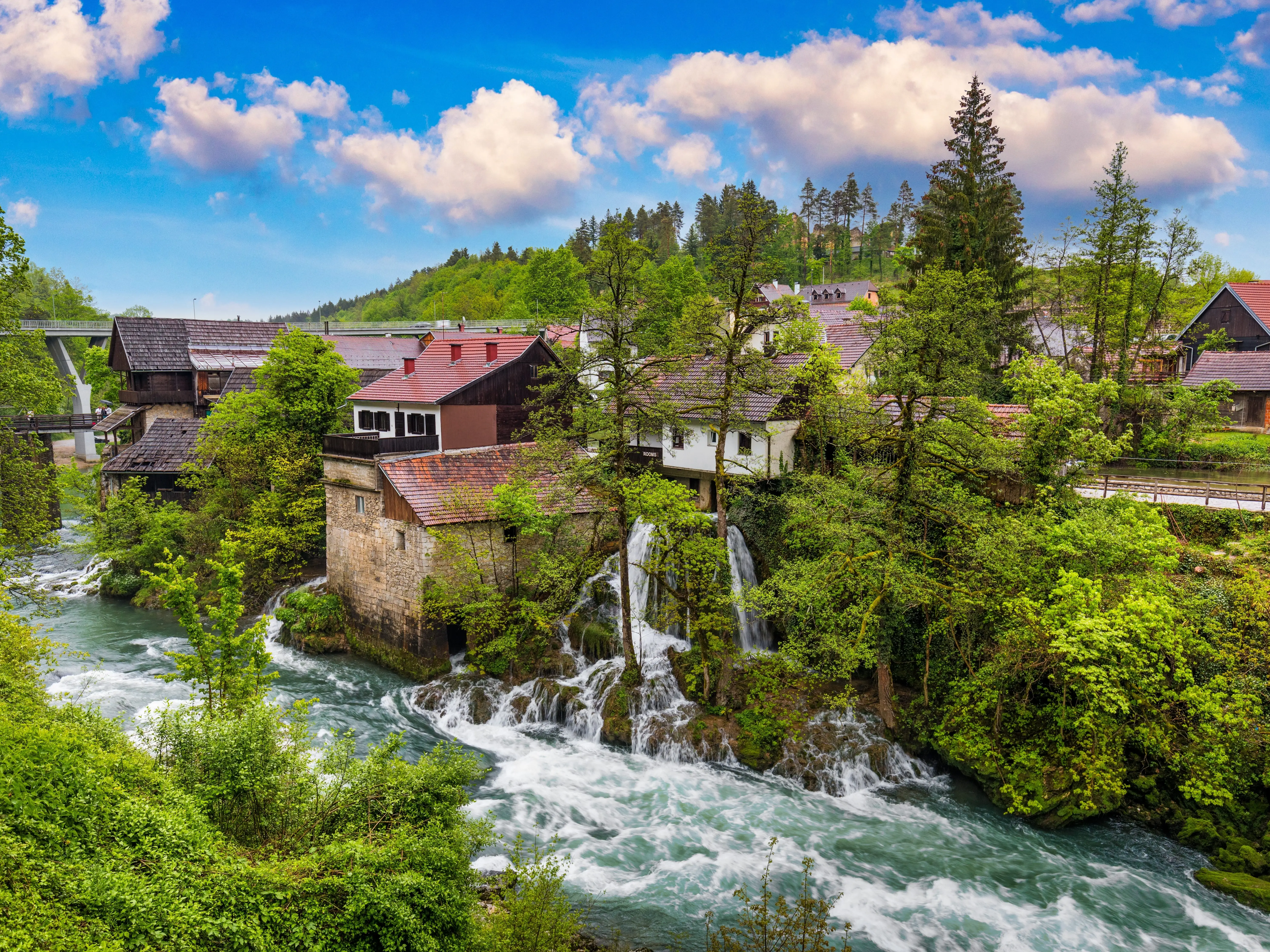 A wide shot of homes and the Korana River in Rastoke, Croatia.