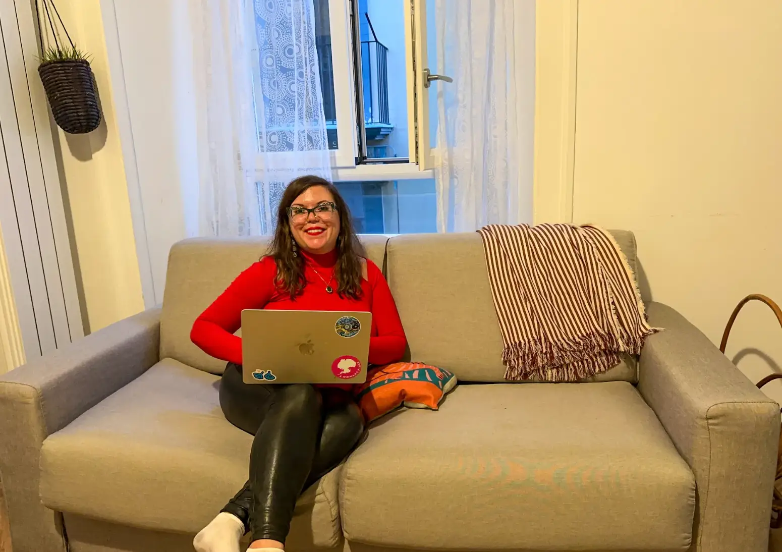 The writer sitting on her couch, using a laptop, in her new Naples apartment.