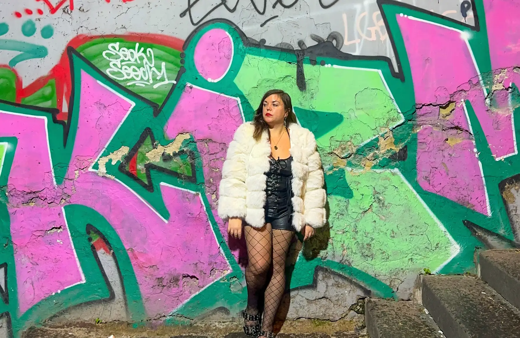 The writer posing in front of a graffitied wall in Naples, Italy.