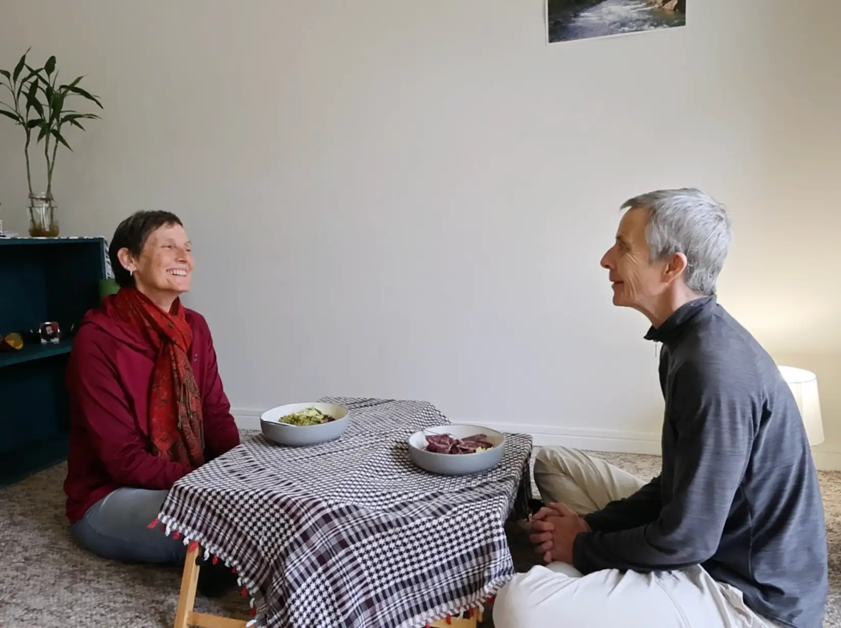 The writer and her partner eating dinner on a small tray table on the floor.