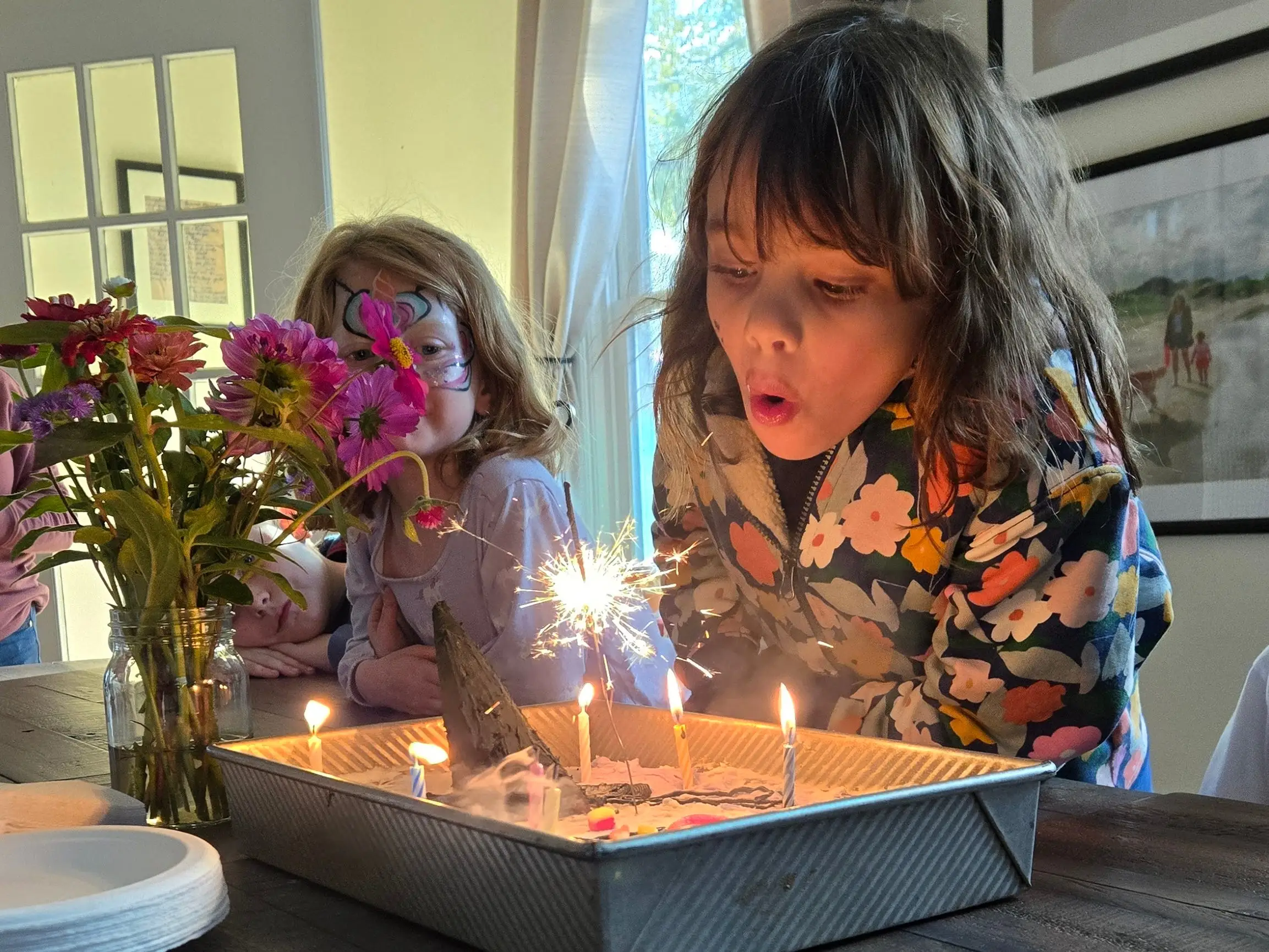 The author's daughter is blowing out candles at her birthday party.