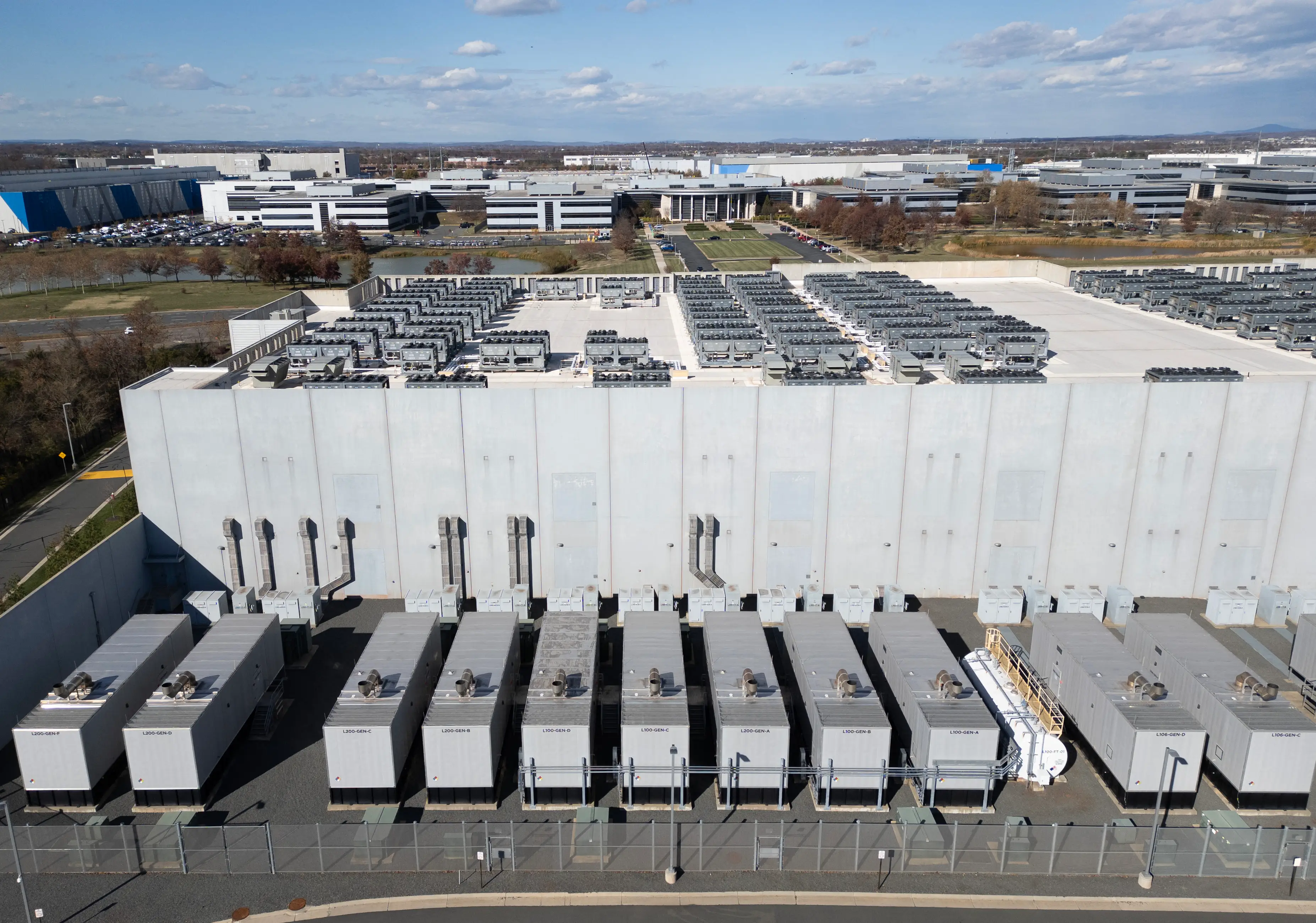 An aerial view shows cooling vent fans on the roof next to generators on the lower level of a data center