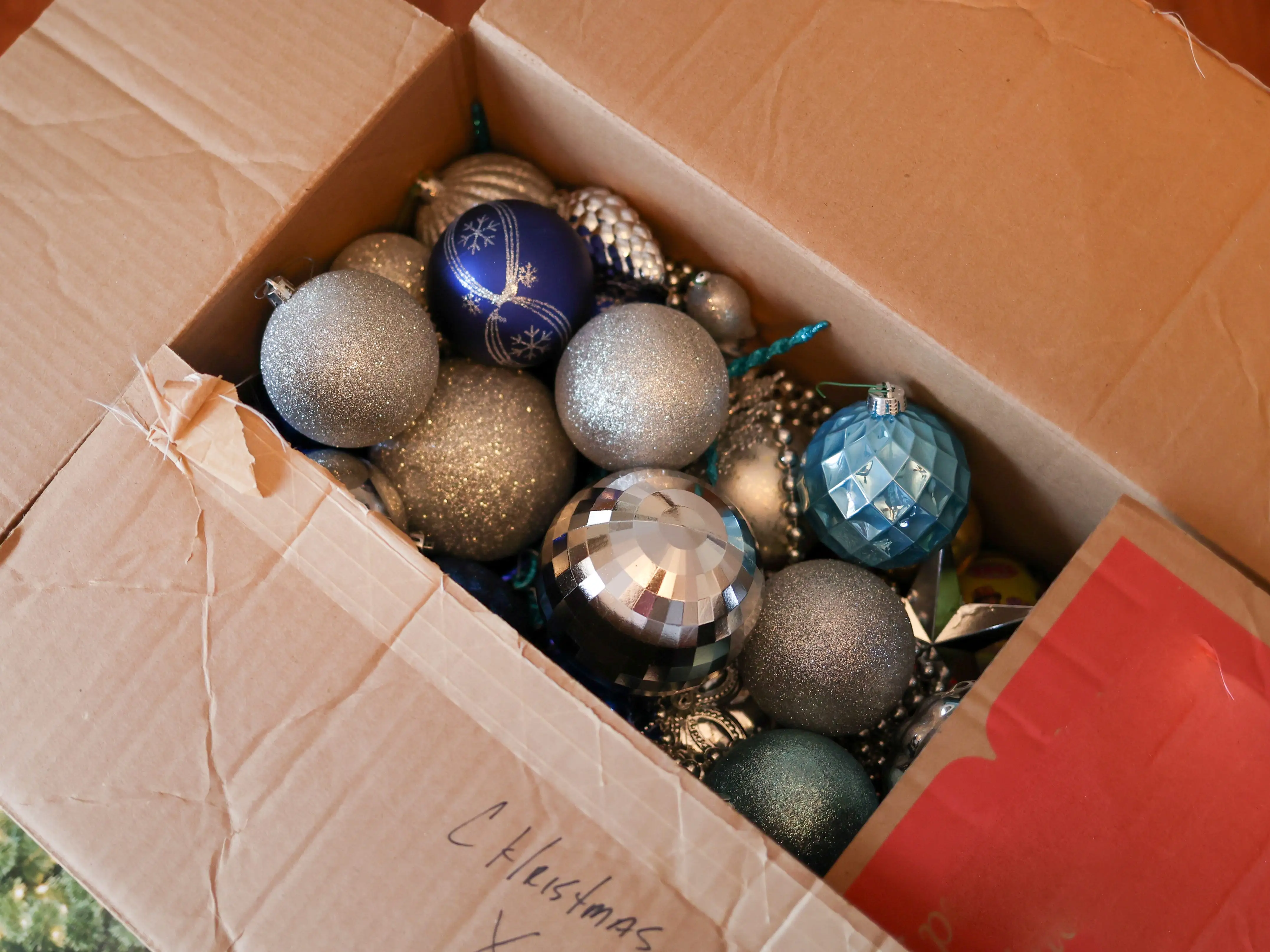 A cardboard box of Christmas ornaments.