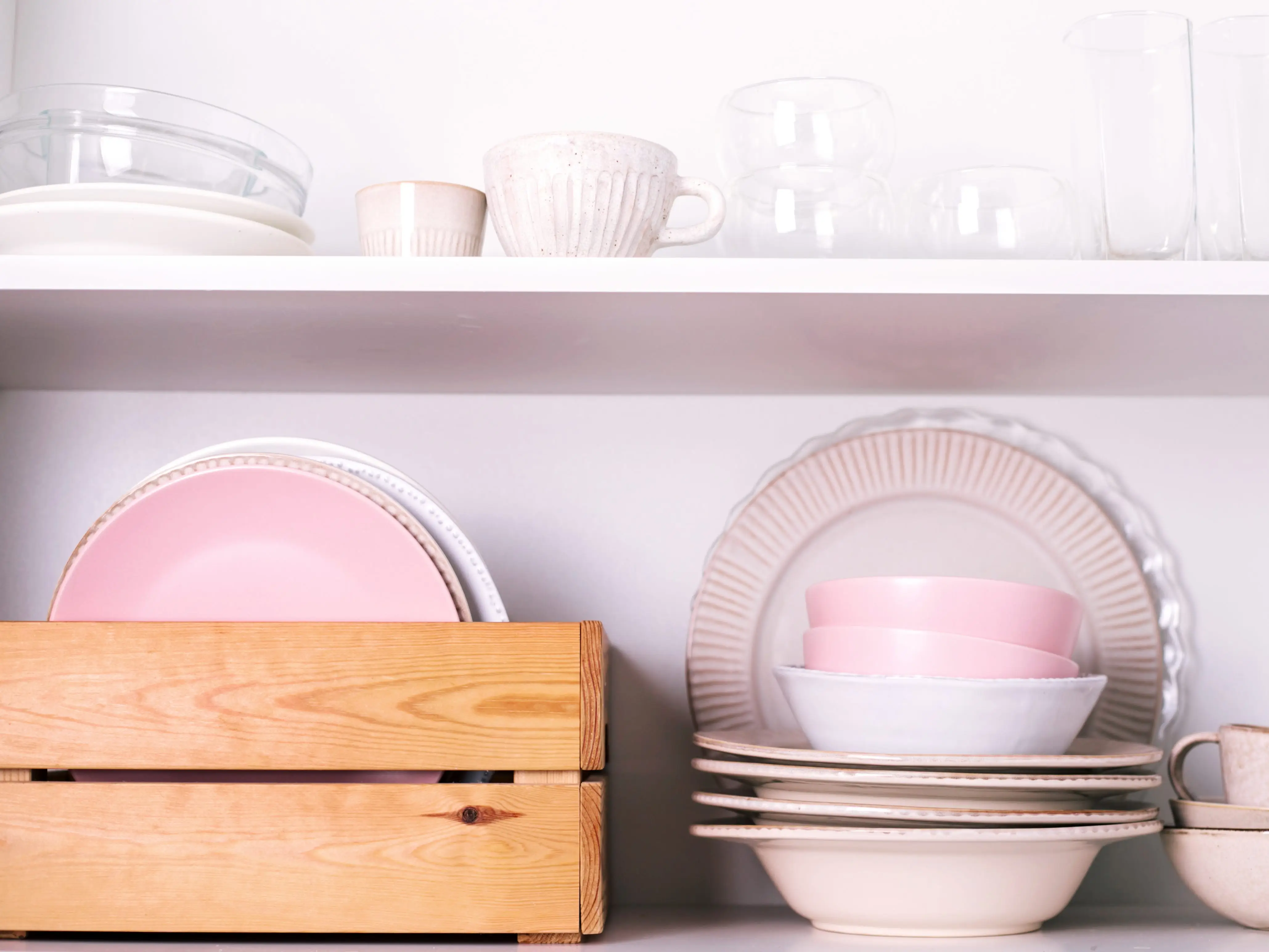 Plates, bowls, cups, and serving platters on shelves in a kitchen.