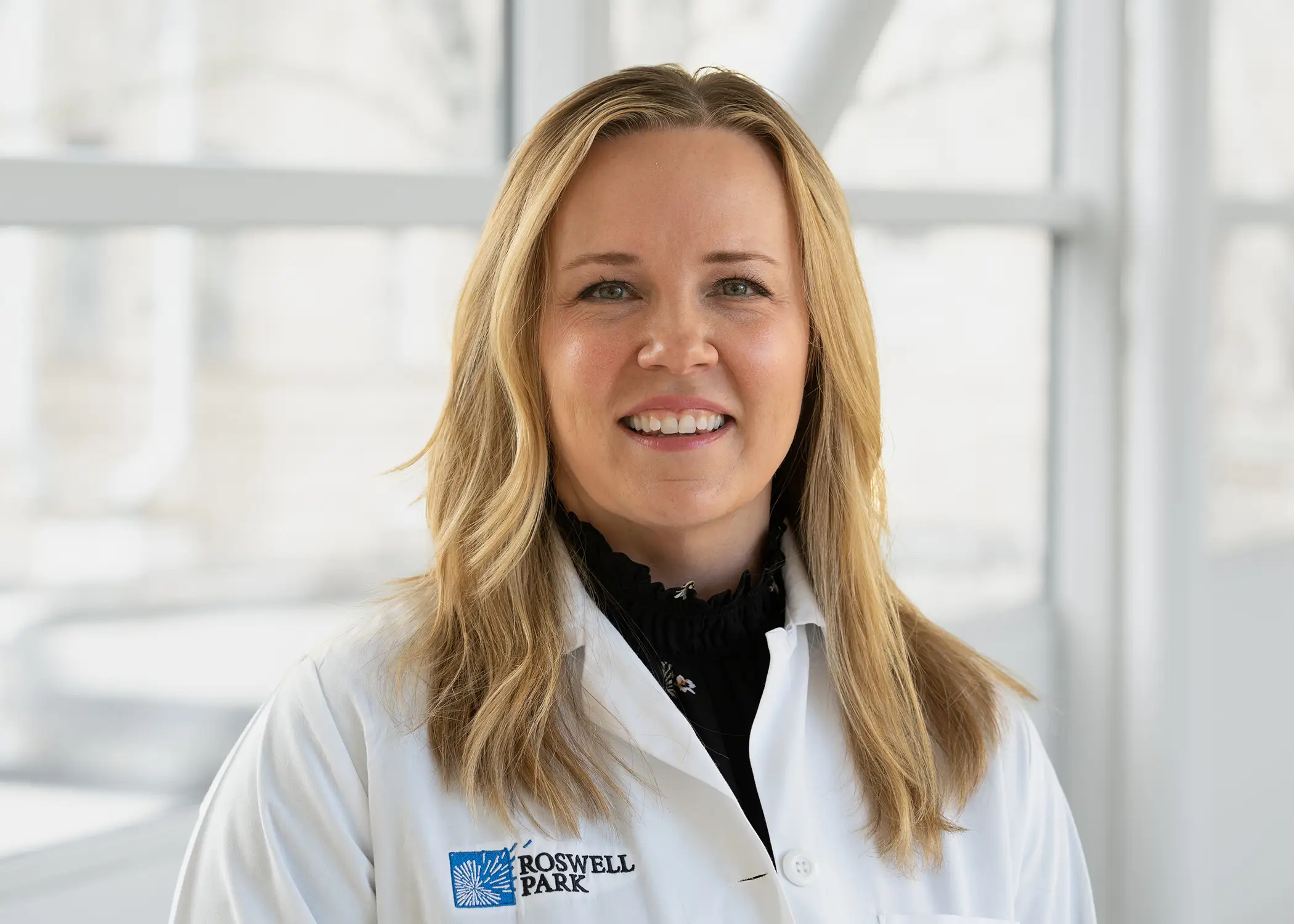 A professional headshot of doctor Shernan Holtan: she has long blond hair and is wearing a white coat that reads