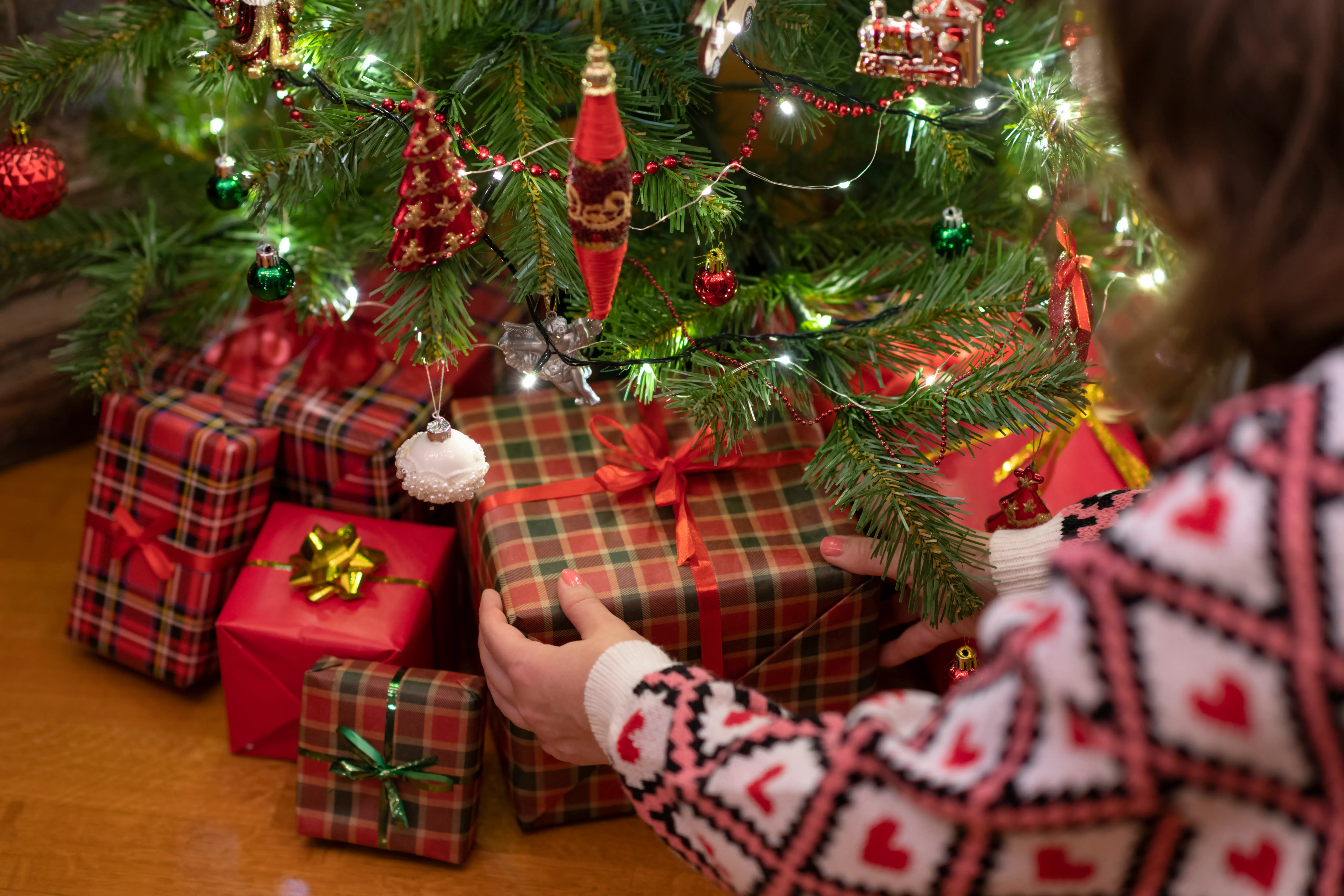 a woman placing a present under the christmas tree