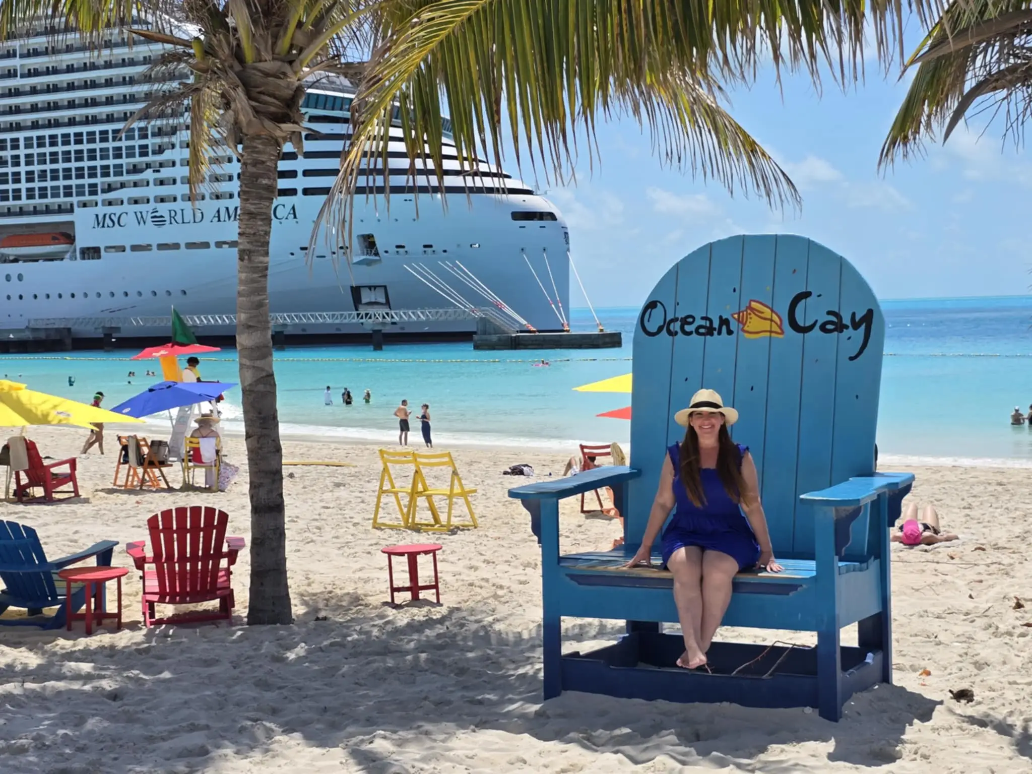 Author Jill Schildhouse sitting on giant chair at Ocean Cay with cruise ship in background