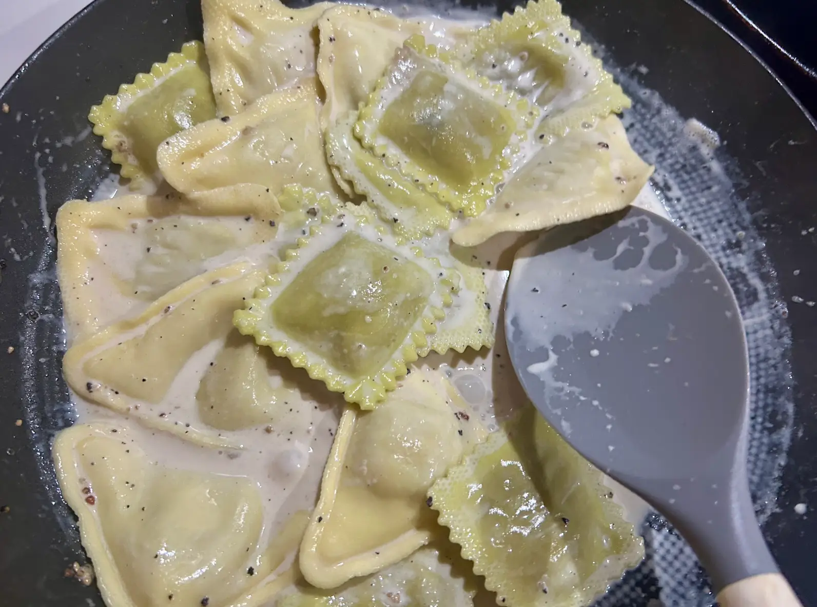 Stirring ravioli into sauce on the skillet.