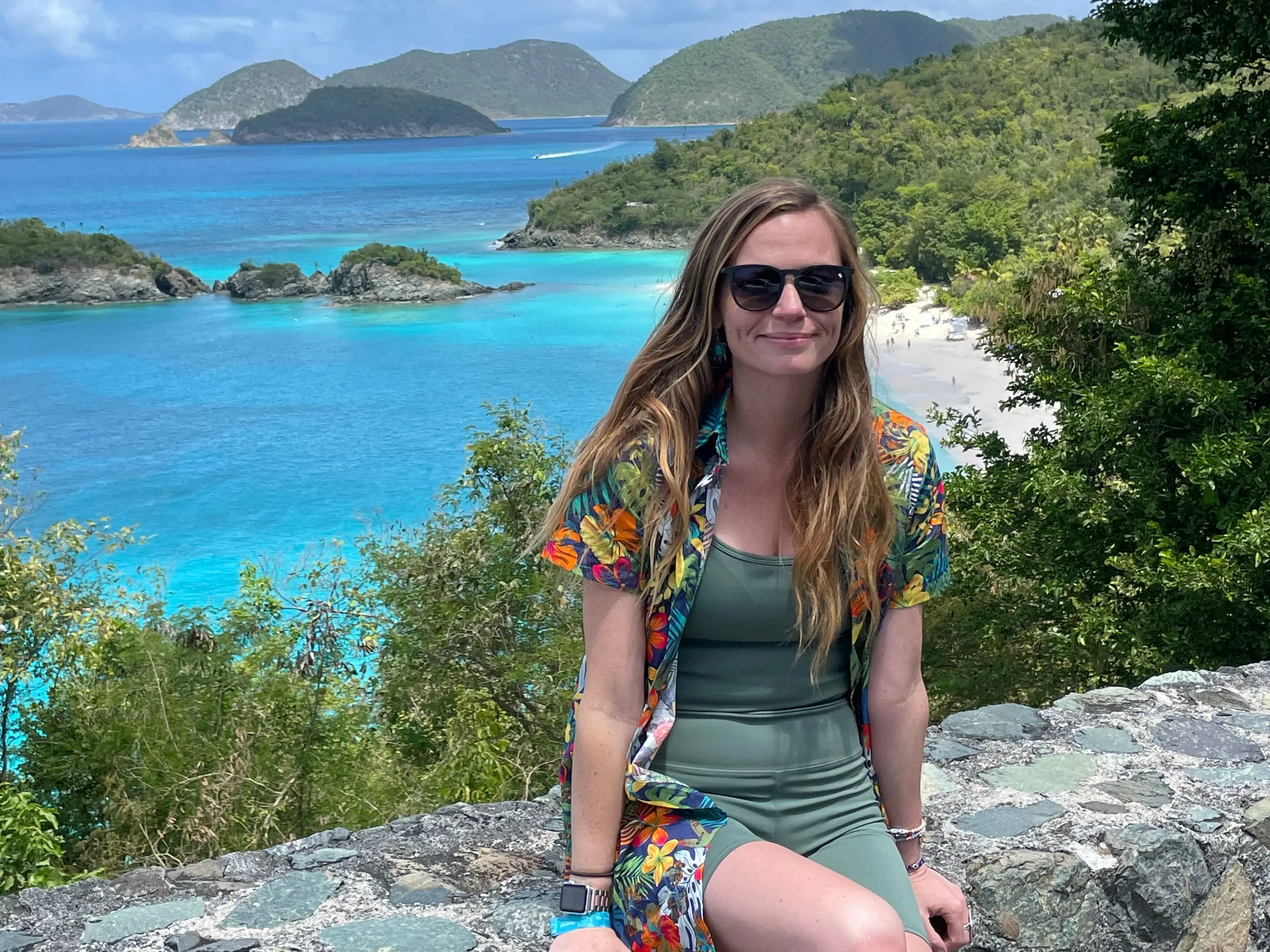 Emily sits on a wall overlooking turquoise water and islands.