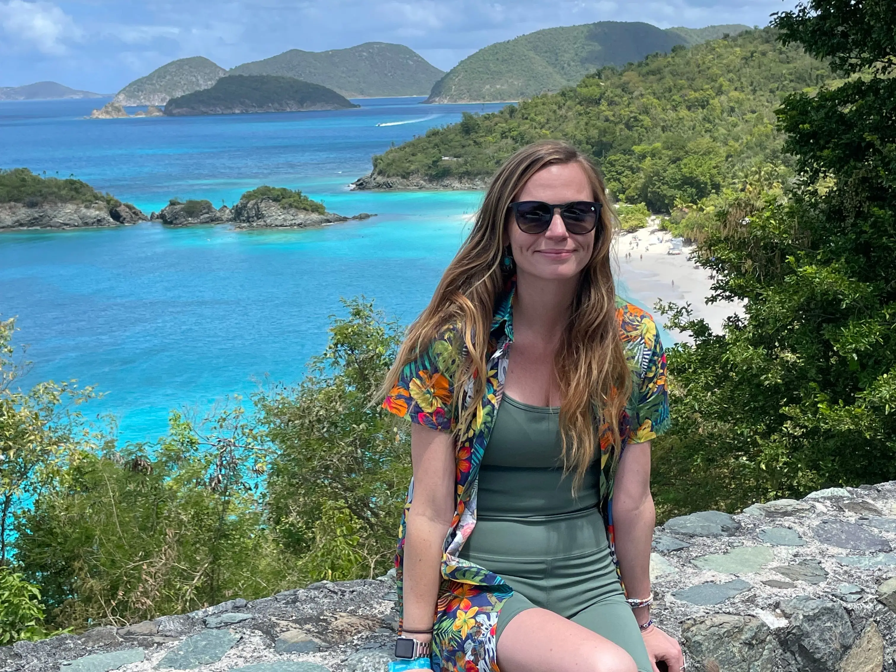 Emily sits on a wall overlooking turquoise water and islands.