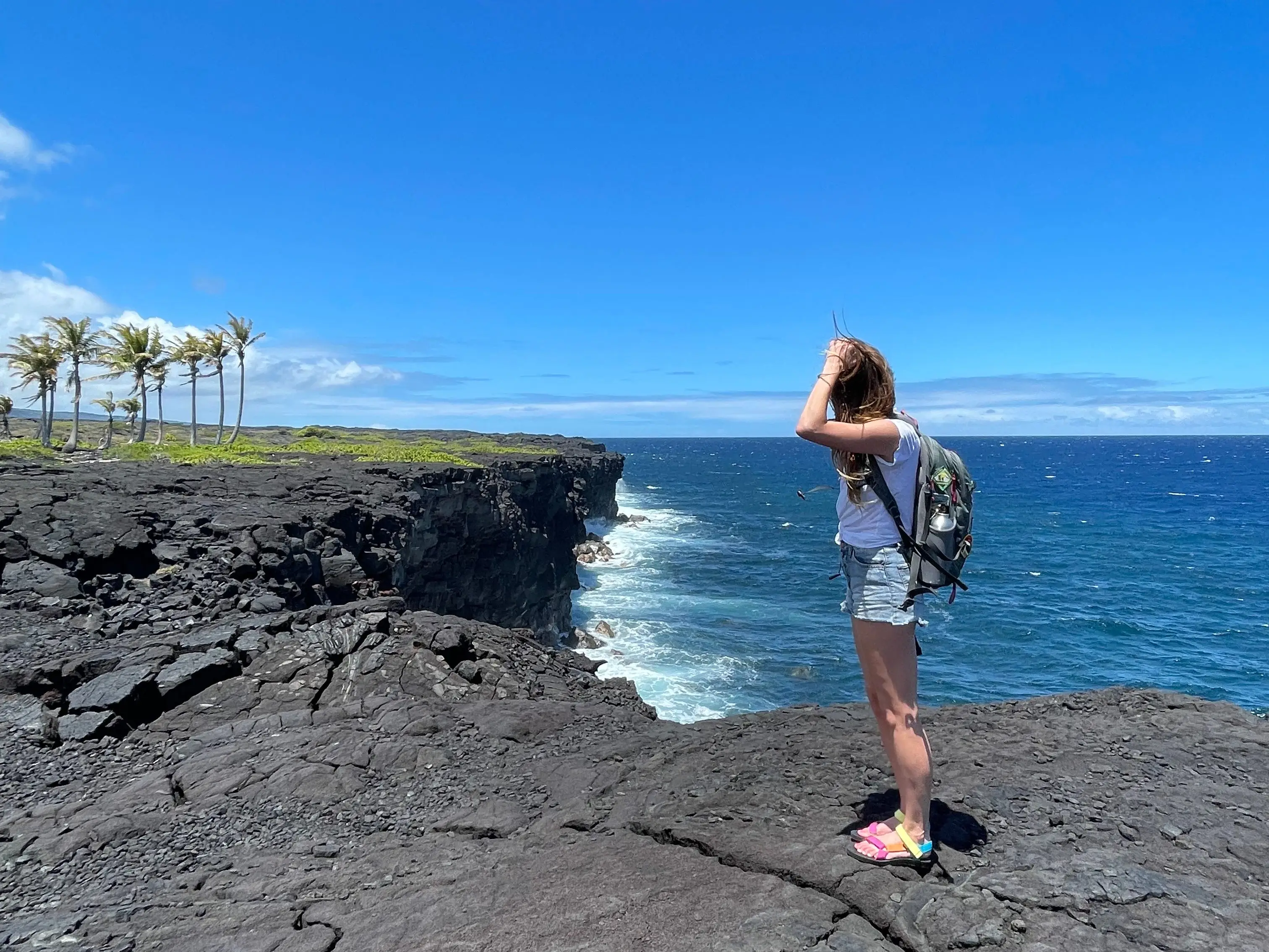 Emily stands near a cliff overlooking the ocean.
